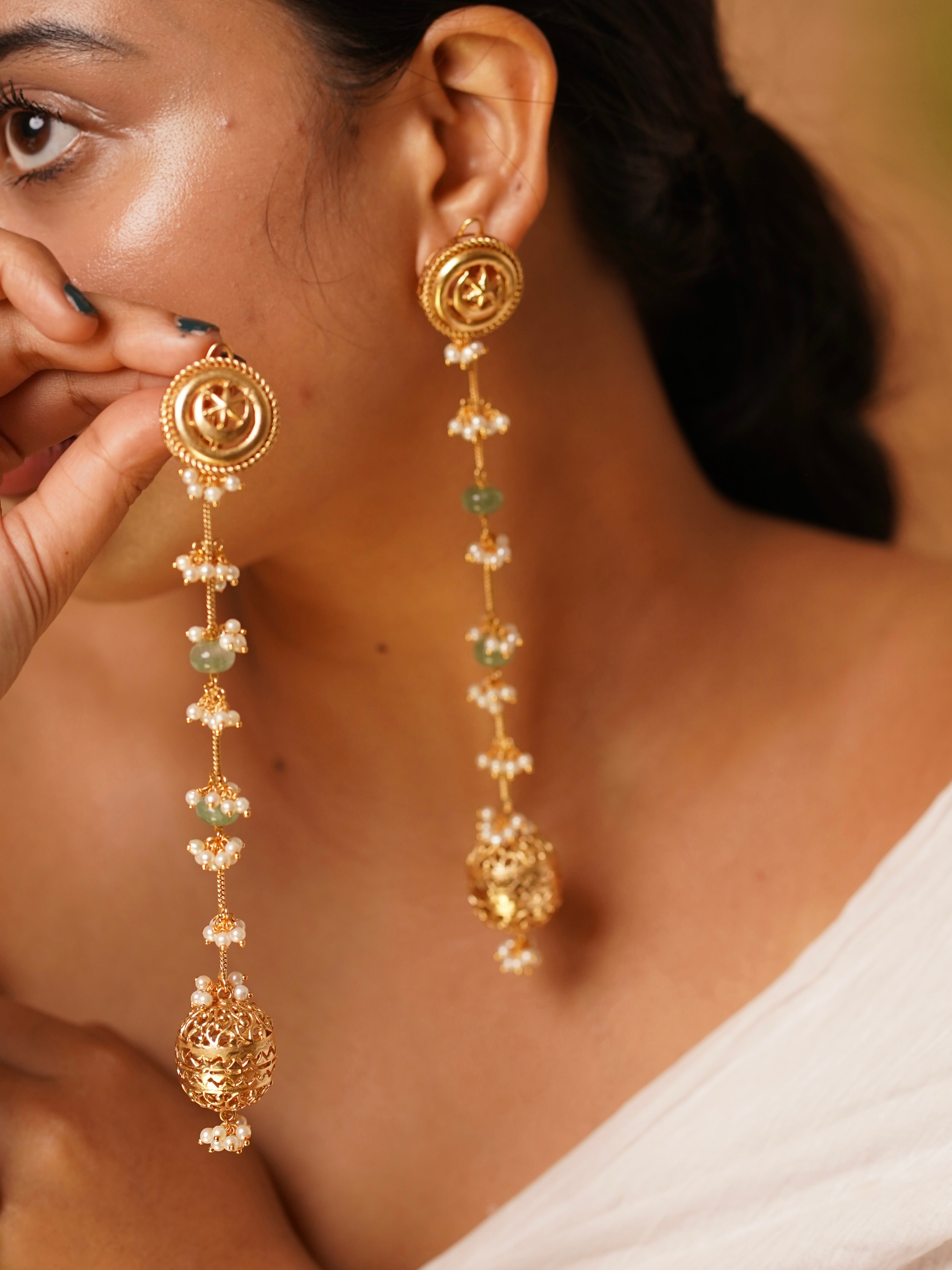 Angled view of long Zeenat drop earrings with ornate jhumka and pastel gem embellishments