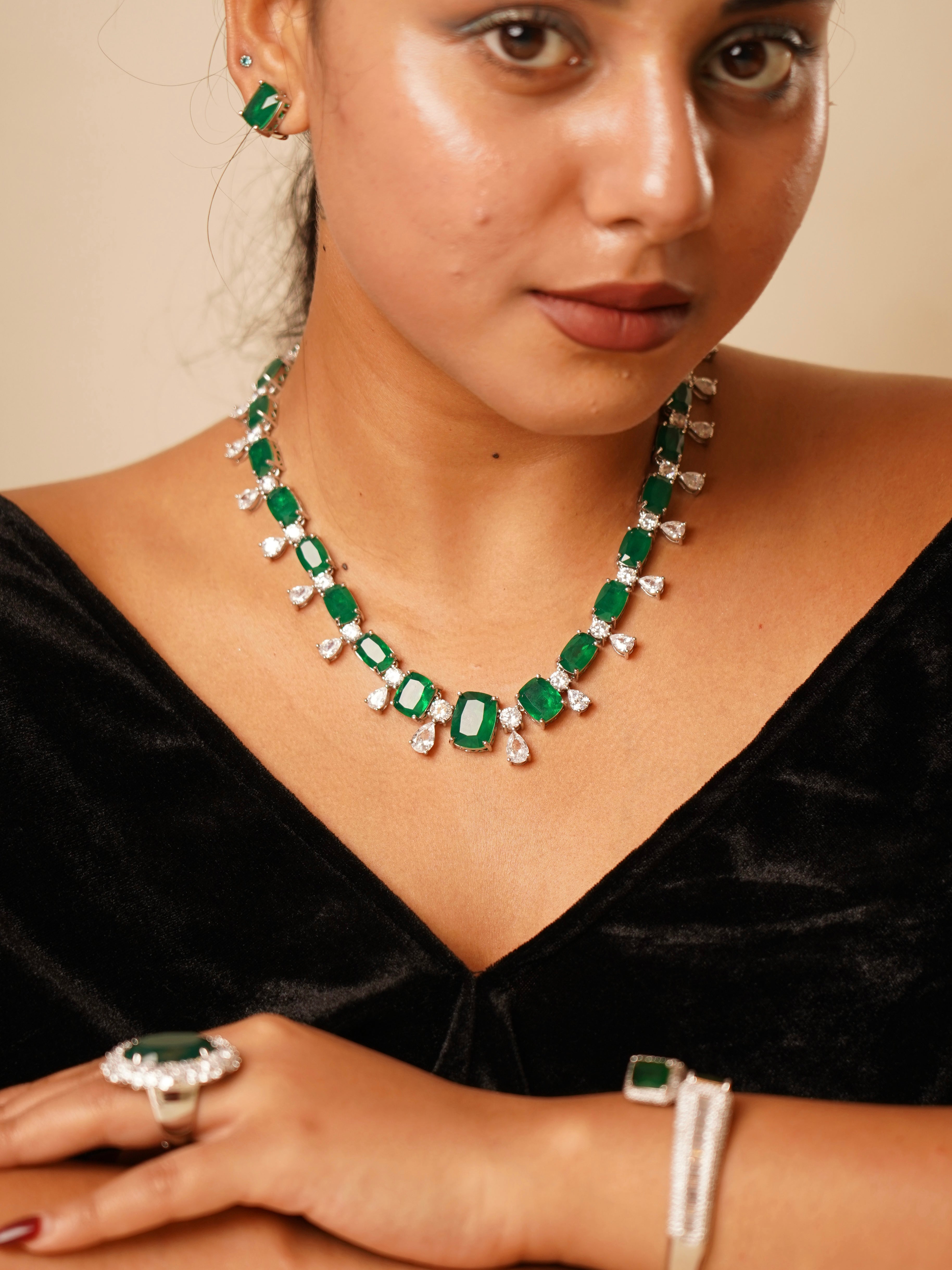 Emerald green necklace with cushion-cut stones and moissanite teardrops, styled in silver tone