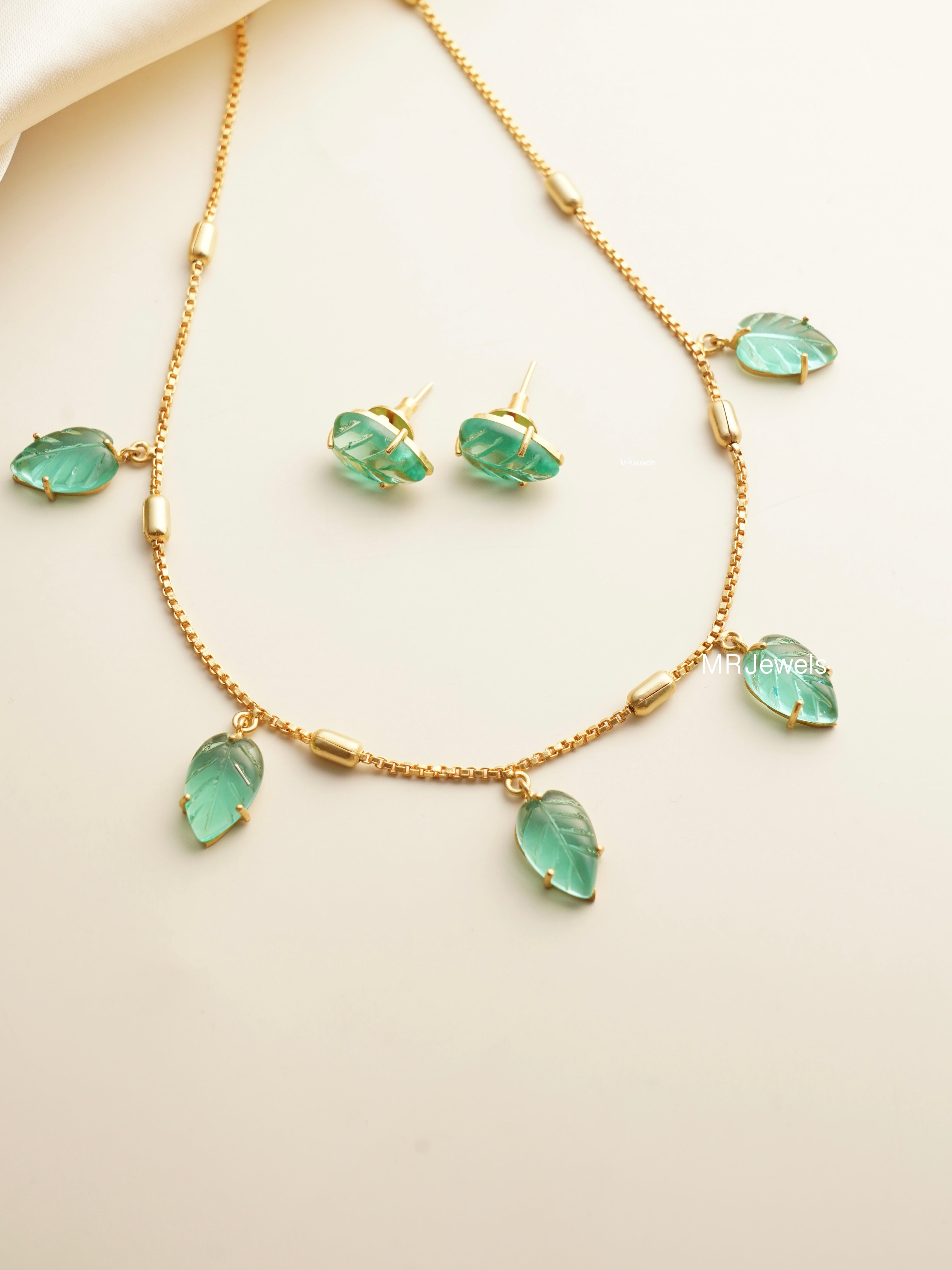 Earring close-up from garnet necklace set featuring leaf motif and rich red hue