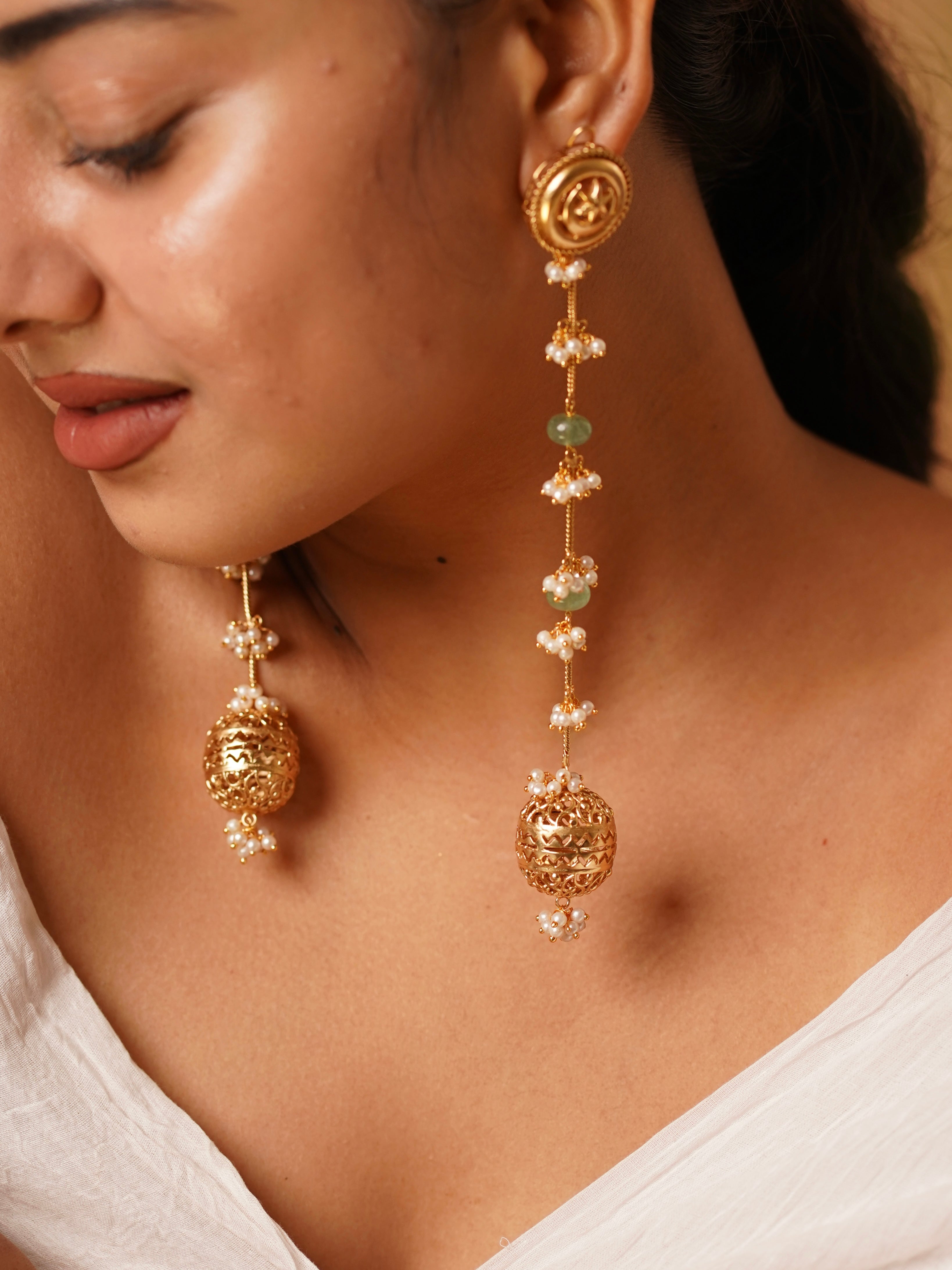 Back view of temple-style earrings highlighting detailed metalwork and hanging pearl elements