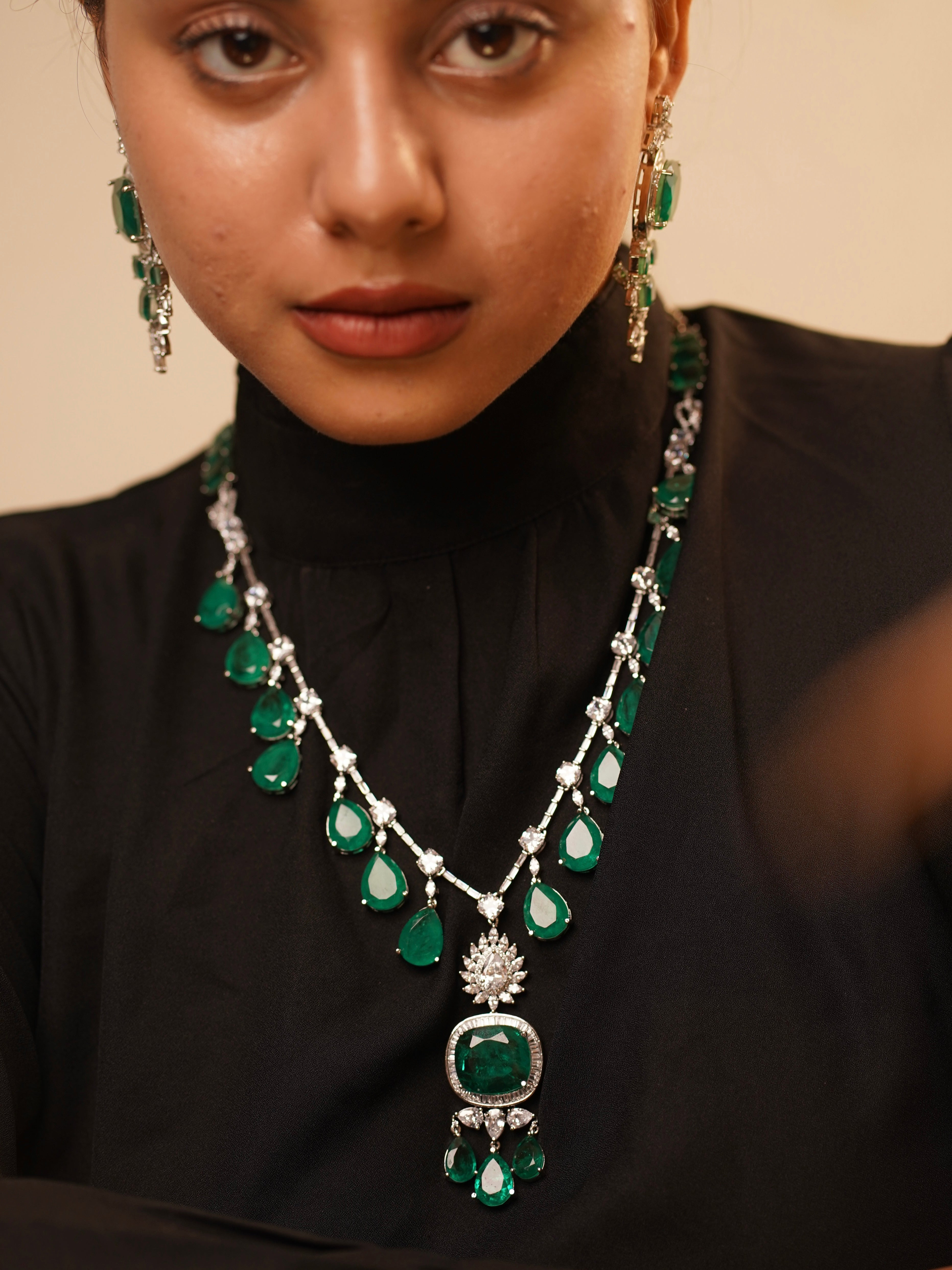 full view of long emerald necklace with dangling stones and matching earring set