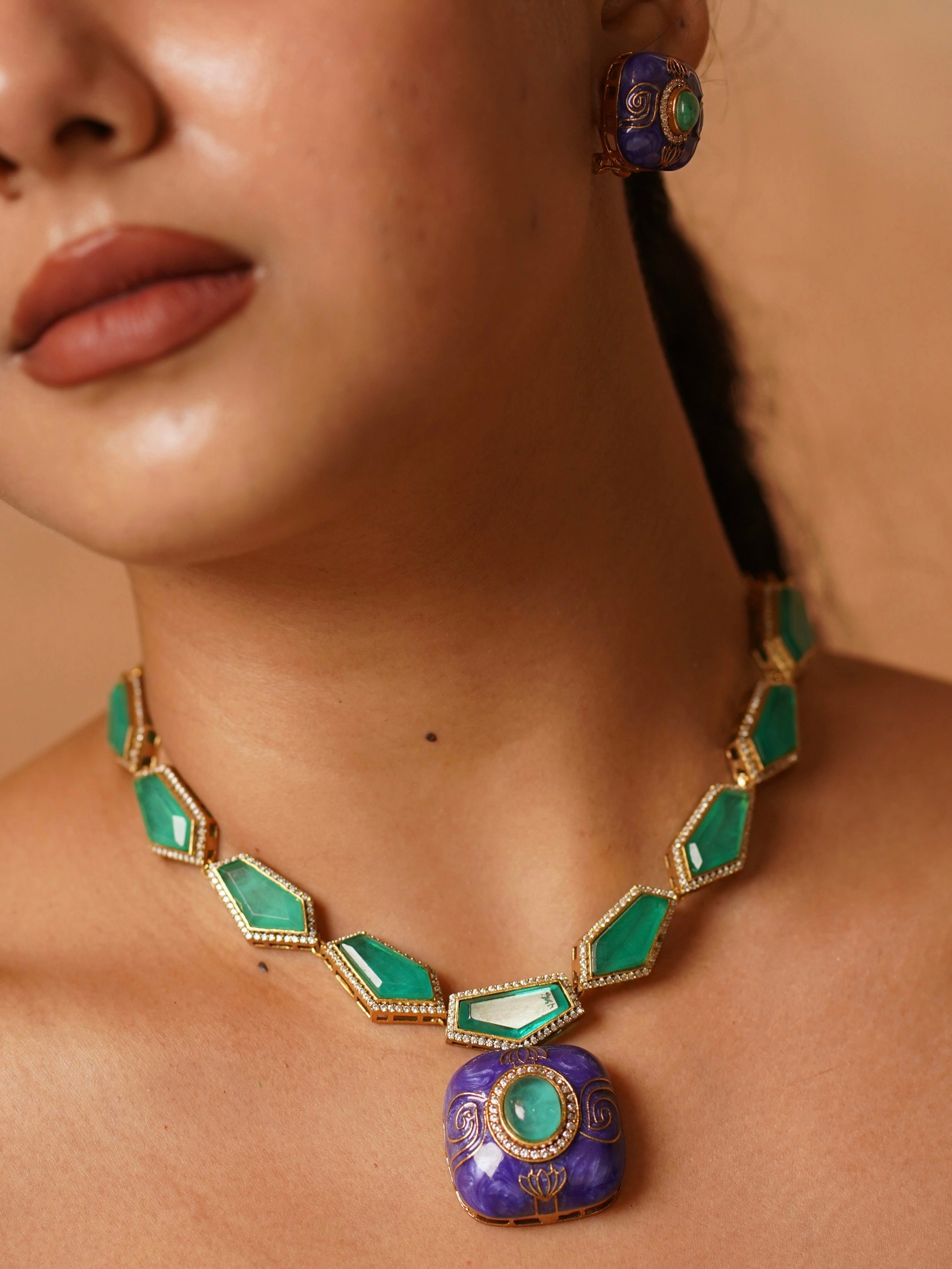 Close-up of lavender enamel pendant with green stone and matching stud earrings