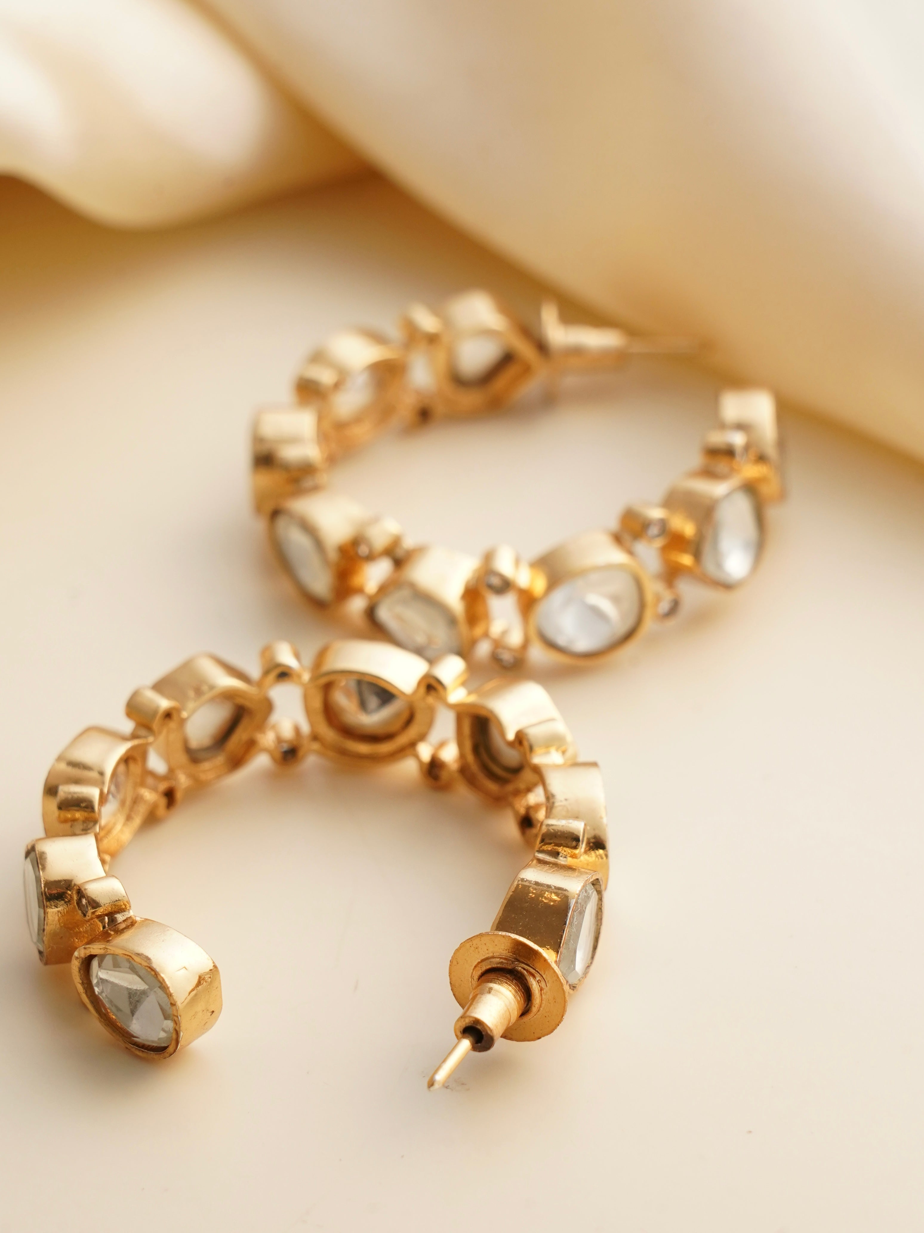 Side view of kundan hoops with red enamel accents and dangling floral charm