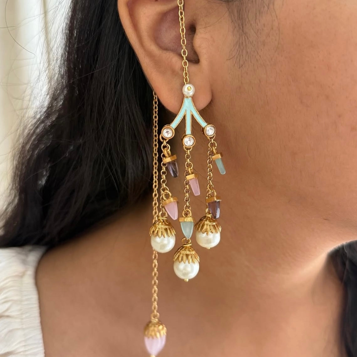 Close-up angled detail of layered pearl bead statement earrings