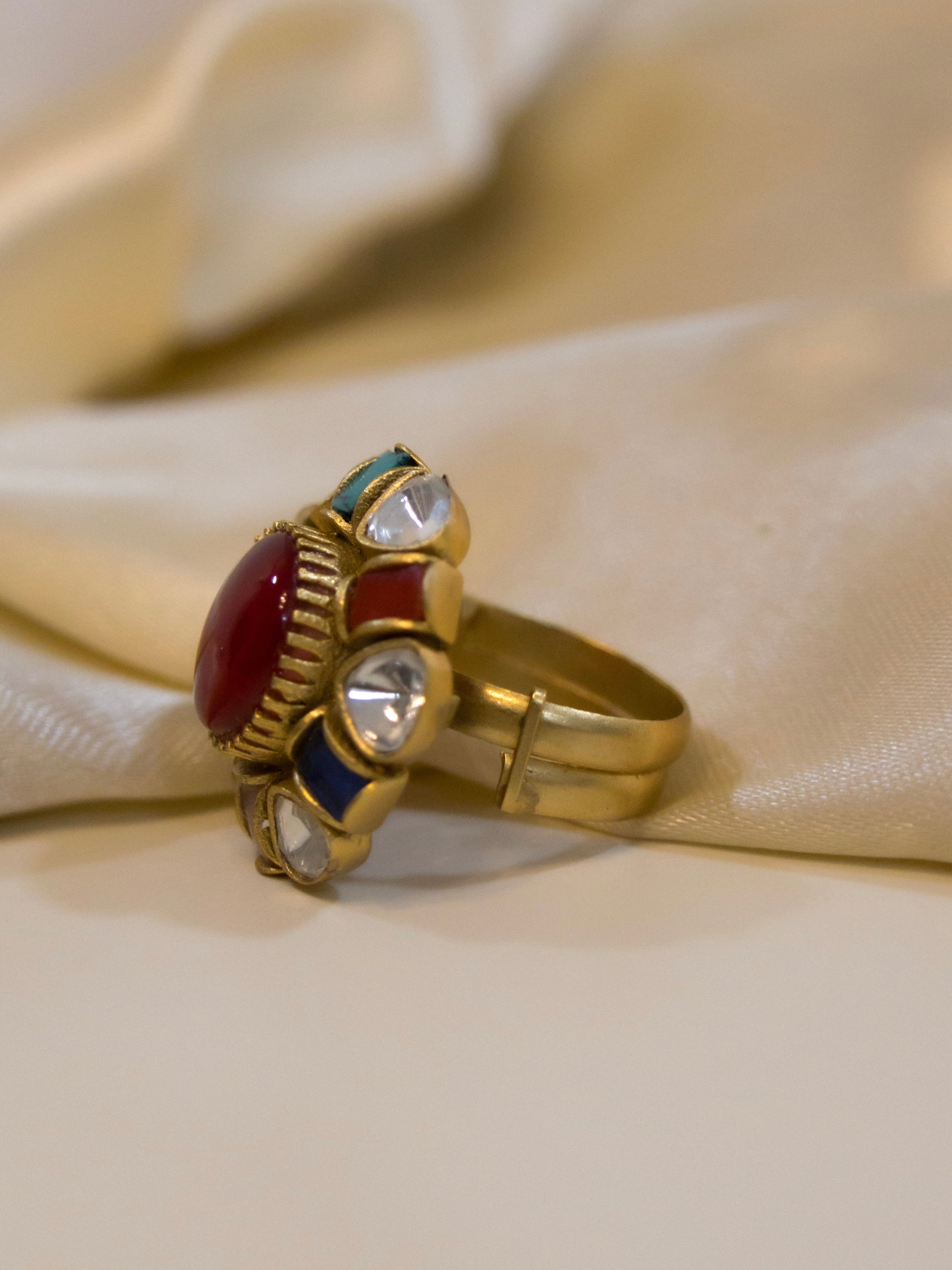Side angle of navratna ring showing antique gold bezel and multicoloured gemstone layout