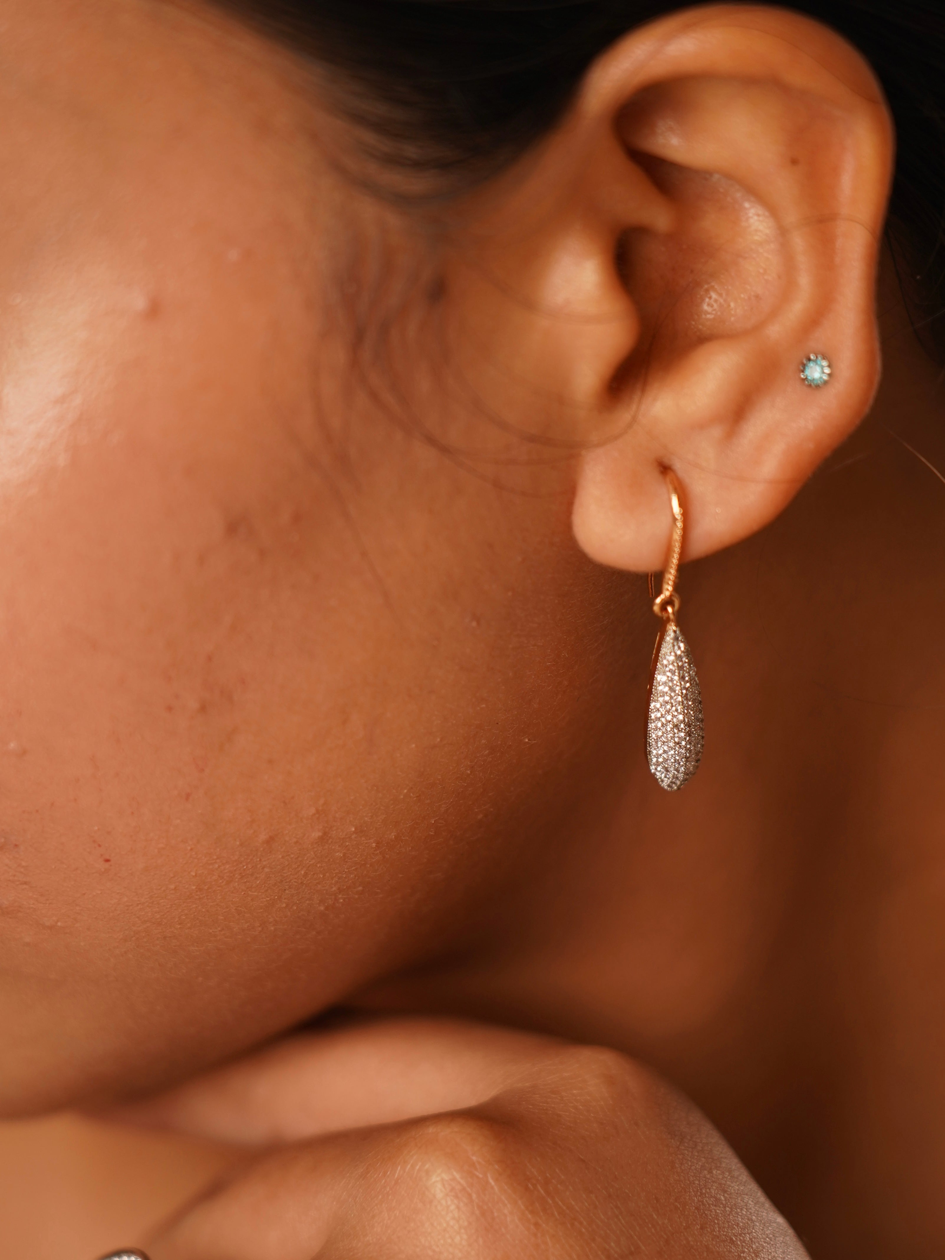 Side angle of diamond dust earrings featuring shimmer pave and slim curved drop design