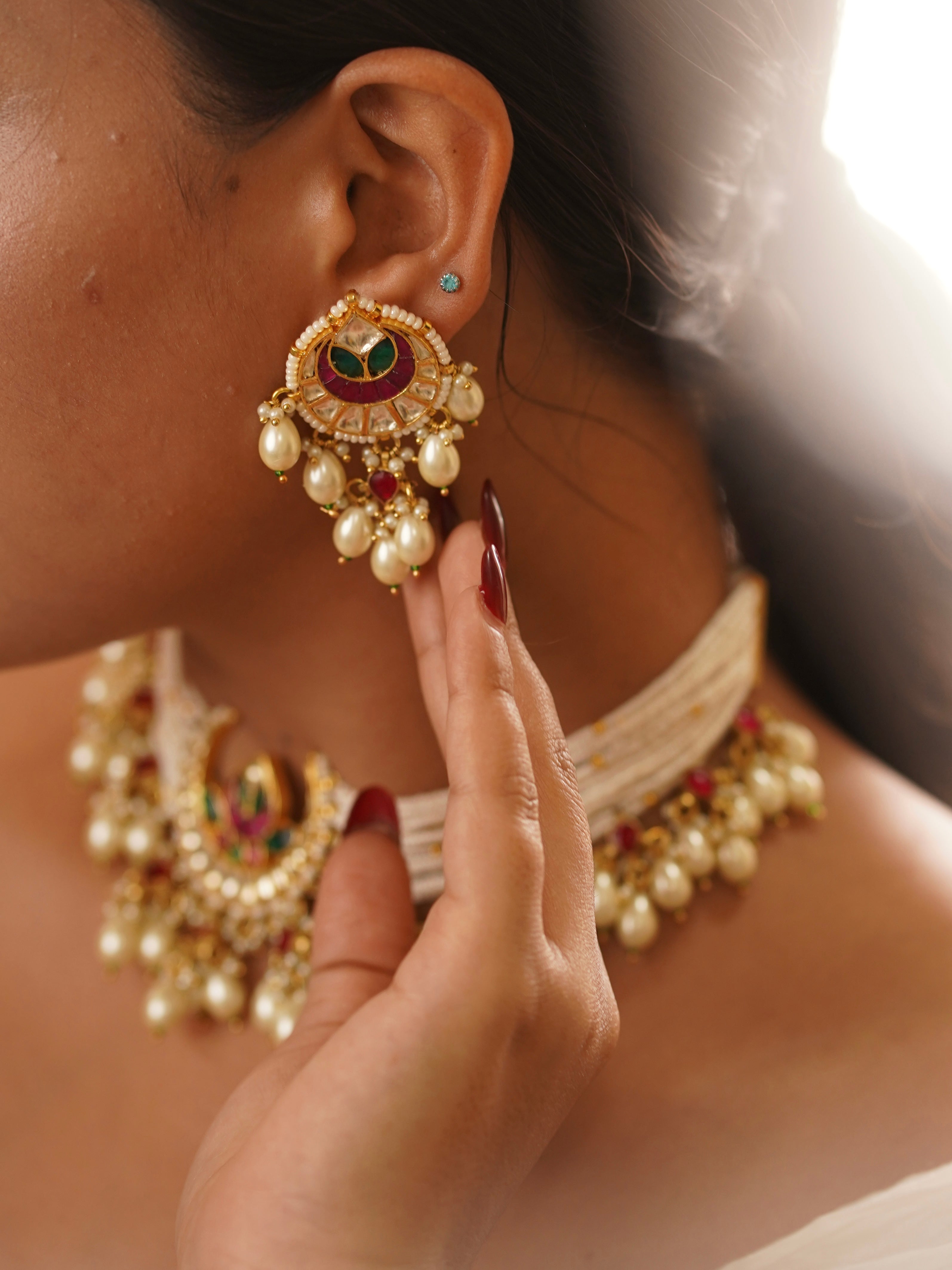 Angled view of meenakari choker with colorful stone centerpiece and pearl string layering