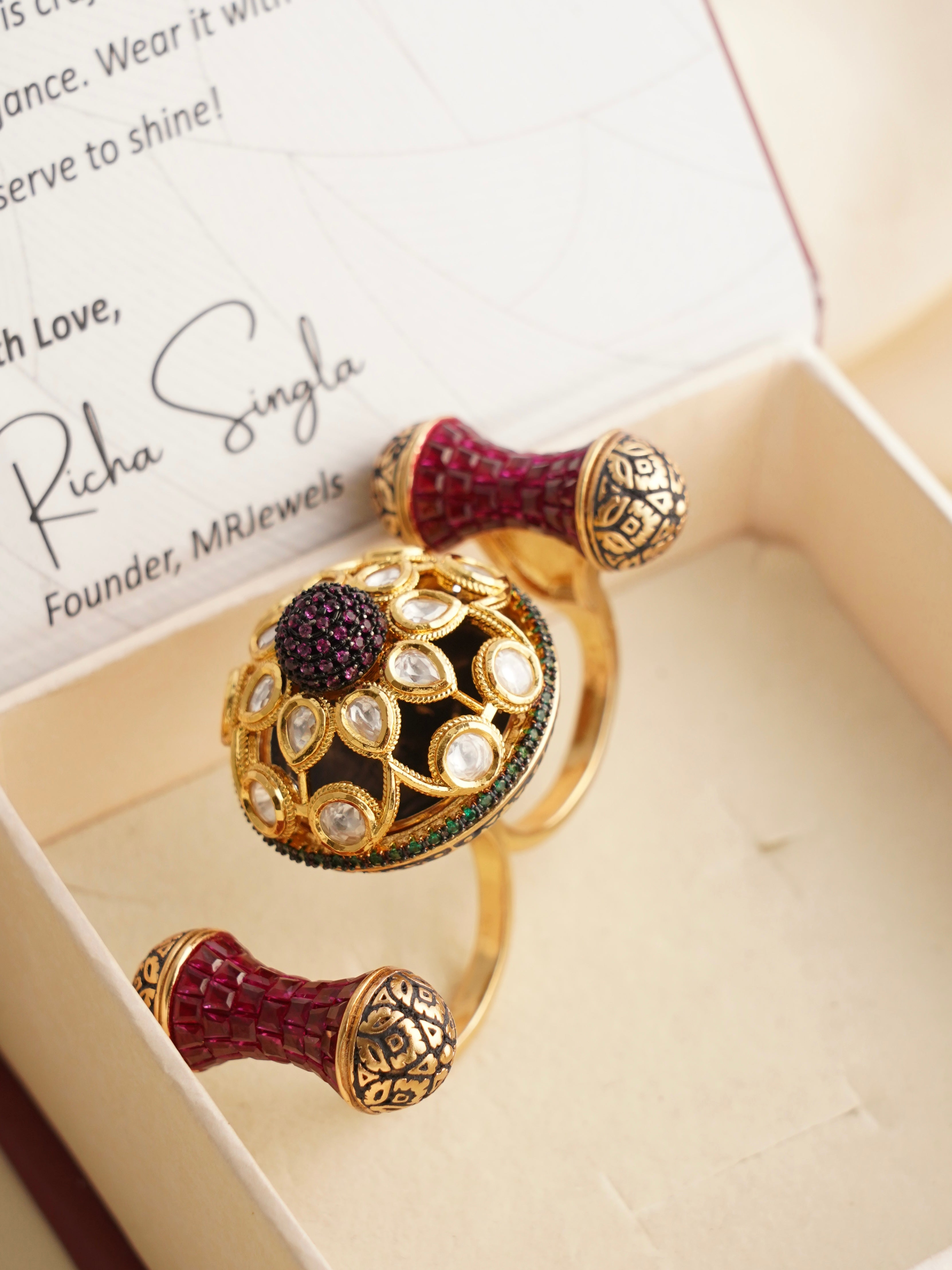 Angled view of statement ruby dual ring with intricate gold patterns and modern form