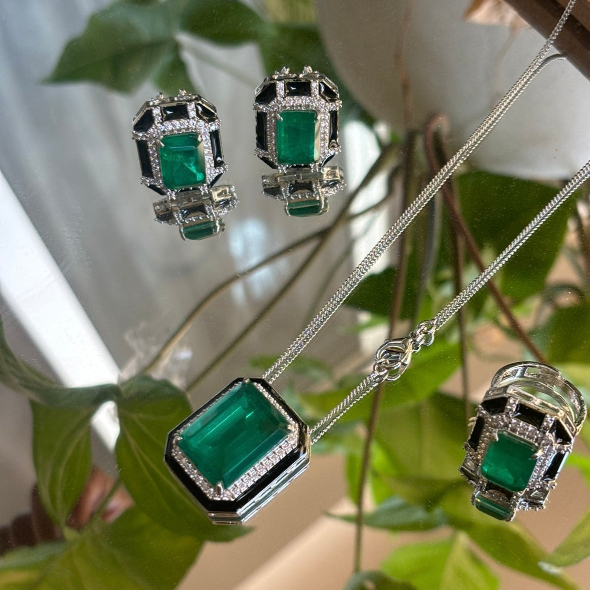 top view of pendant set featuring green doublet stones, enamel highlights and delicate chain