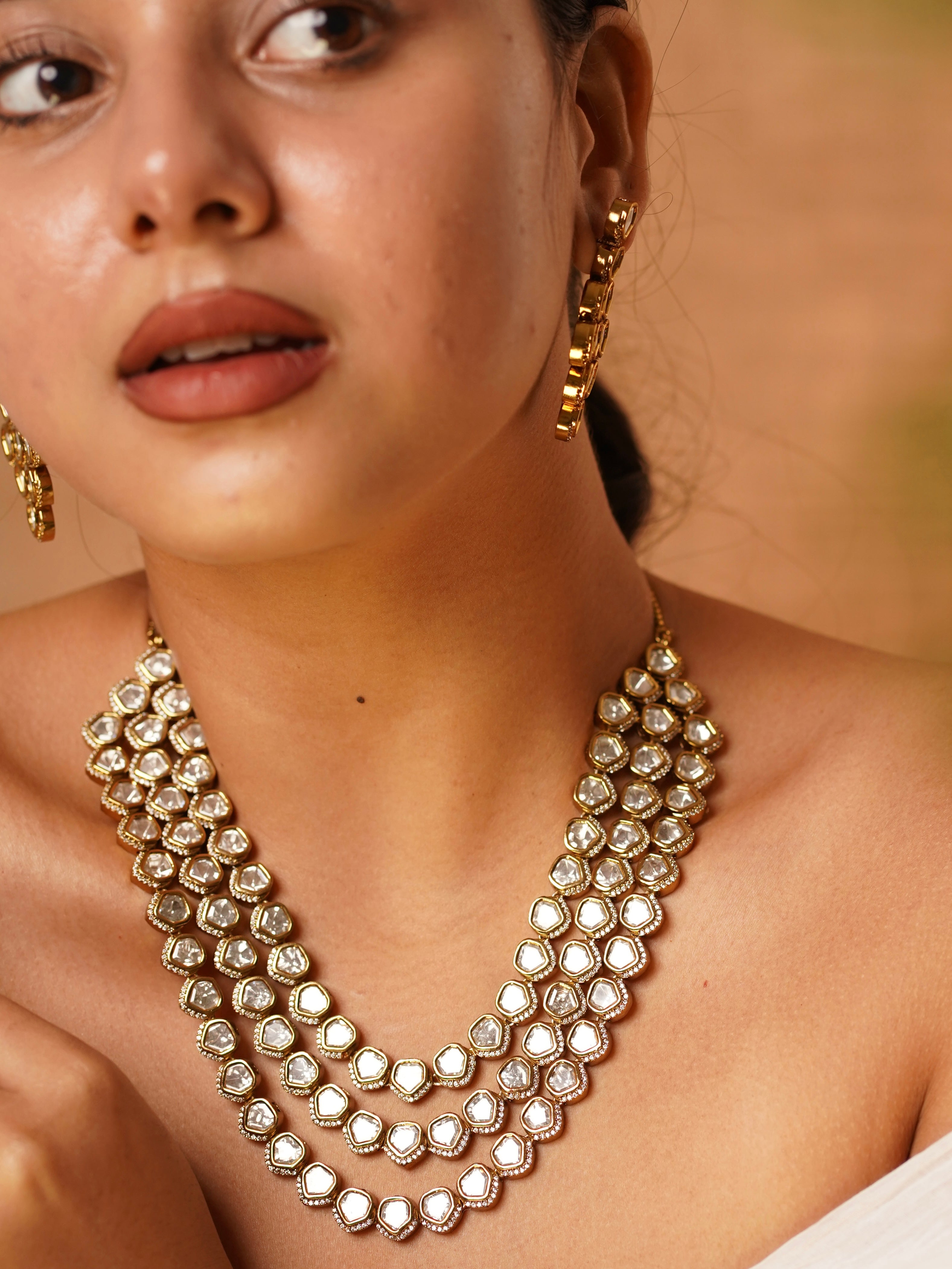 Angled image of kundan set showing earring and necklace detailing with tiered structure