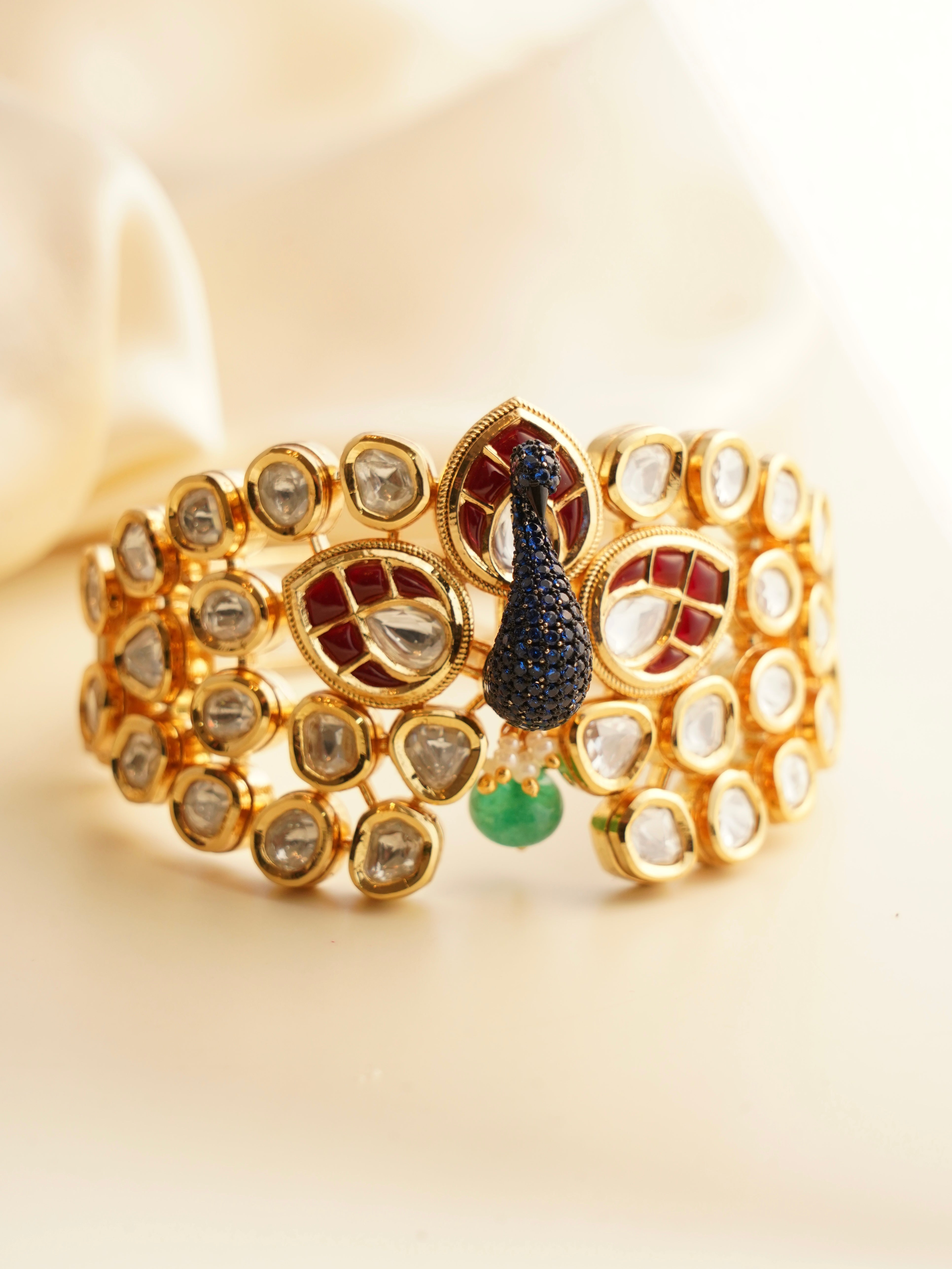 top view of gold bracelet with peacock motif and detailed stonework