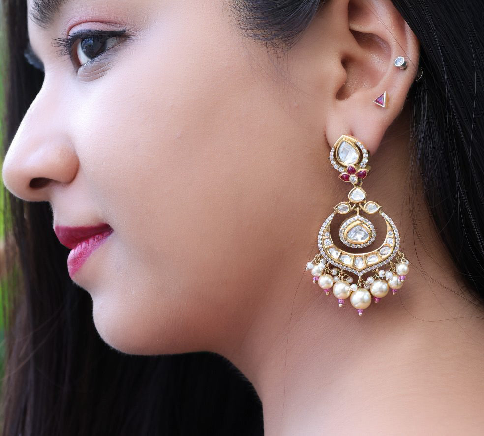 Close-up of kundan chandbali earrings with pearl drops and gold-plated floral detailing