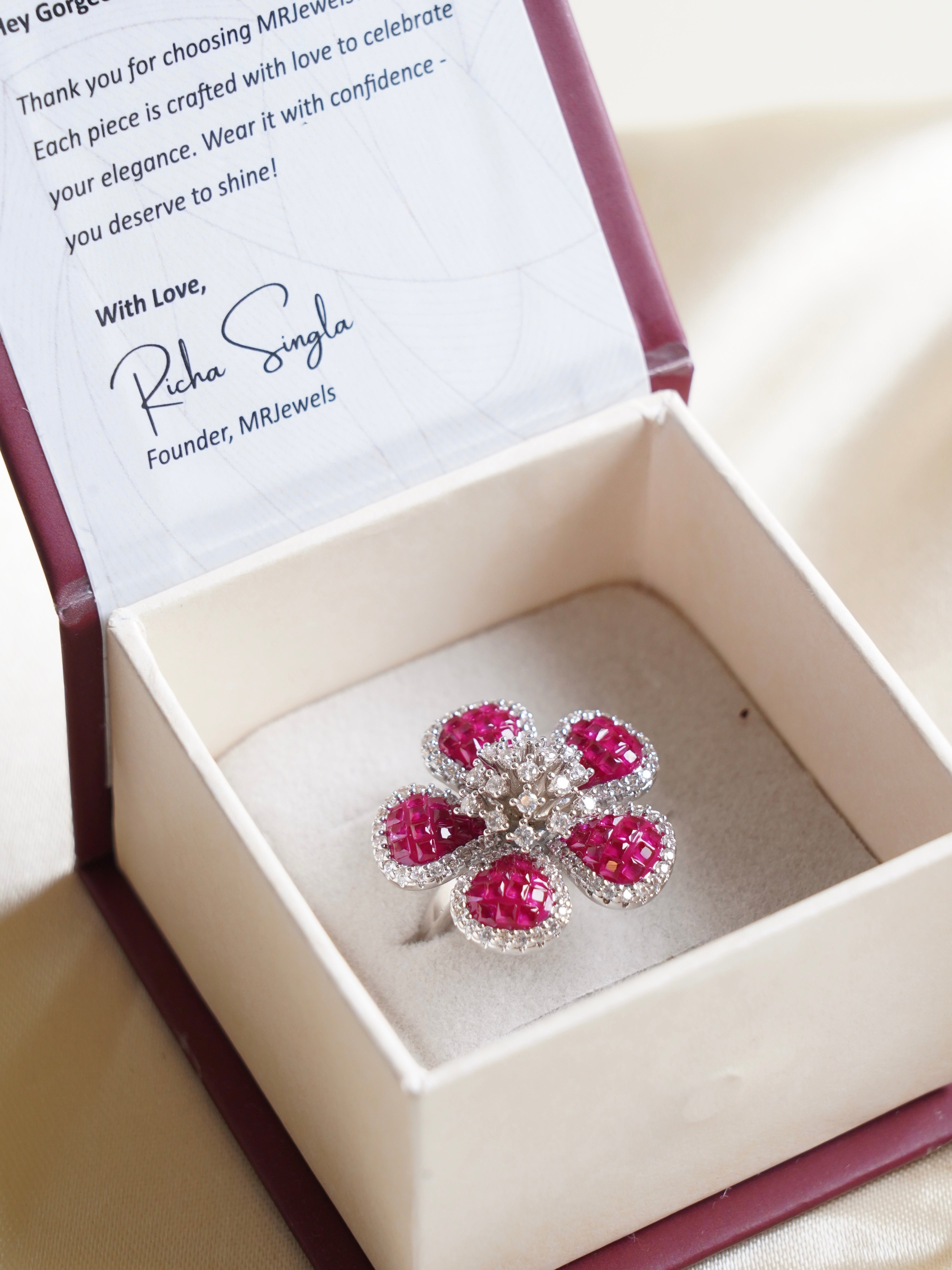 five‑petal ruby baguette flower cocktail ring edged with white crystals on adjustable band