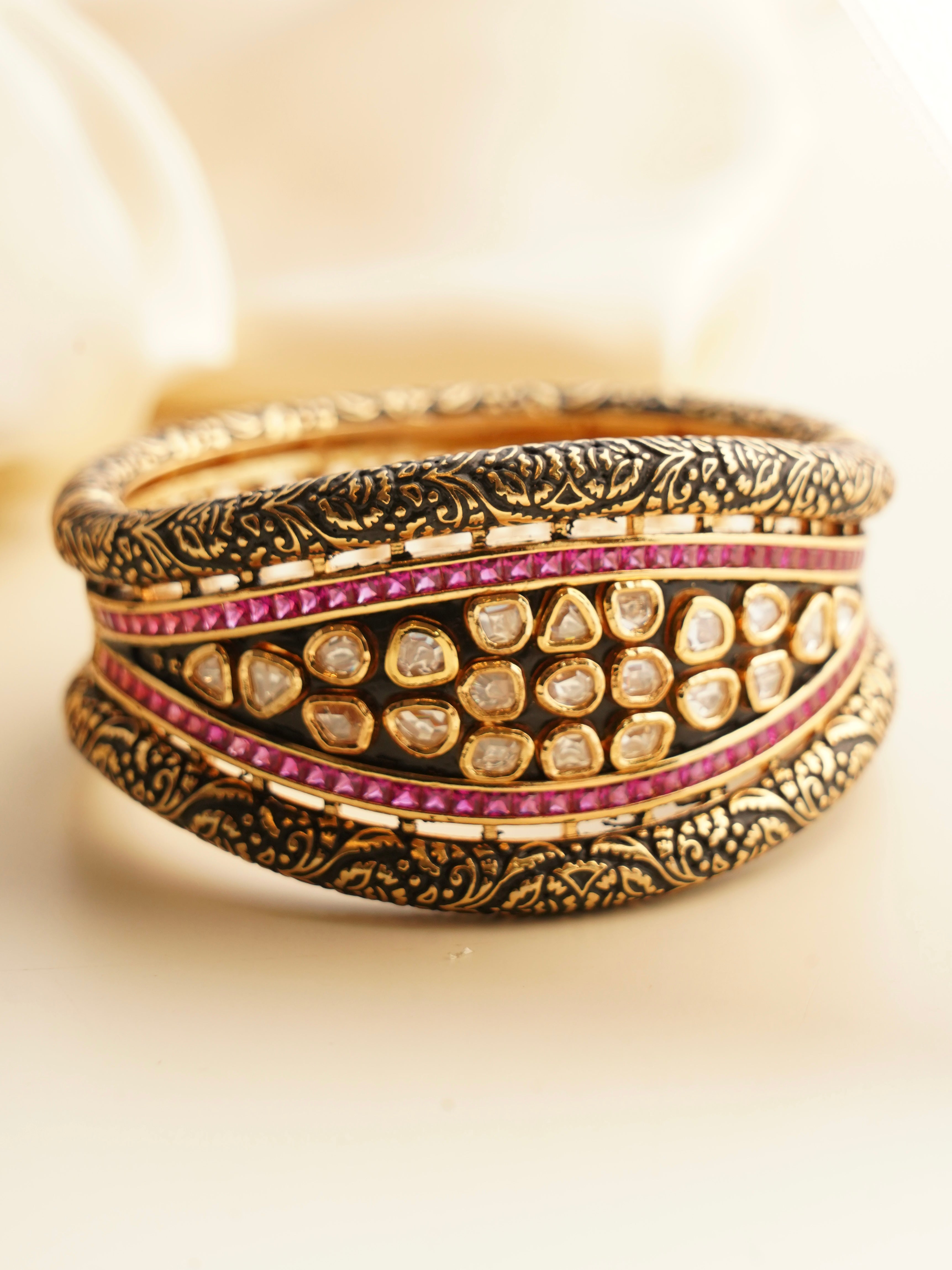 Angled view of antique-style openable bracelet with polki diamonds and ruby accents