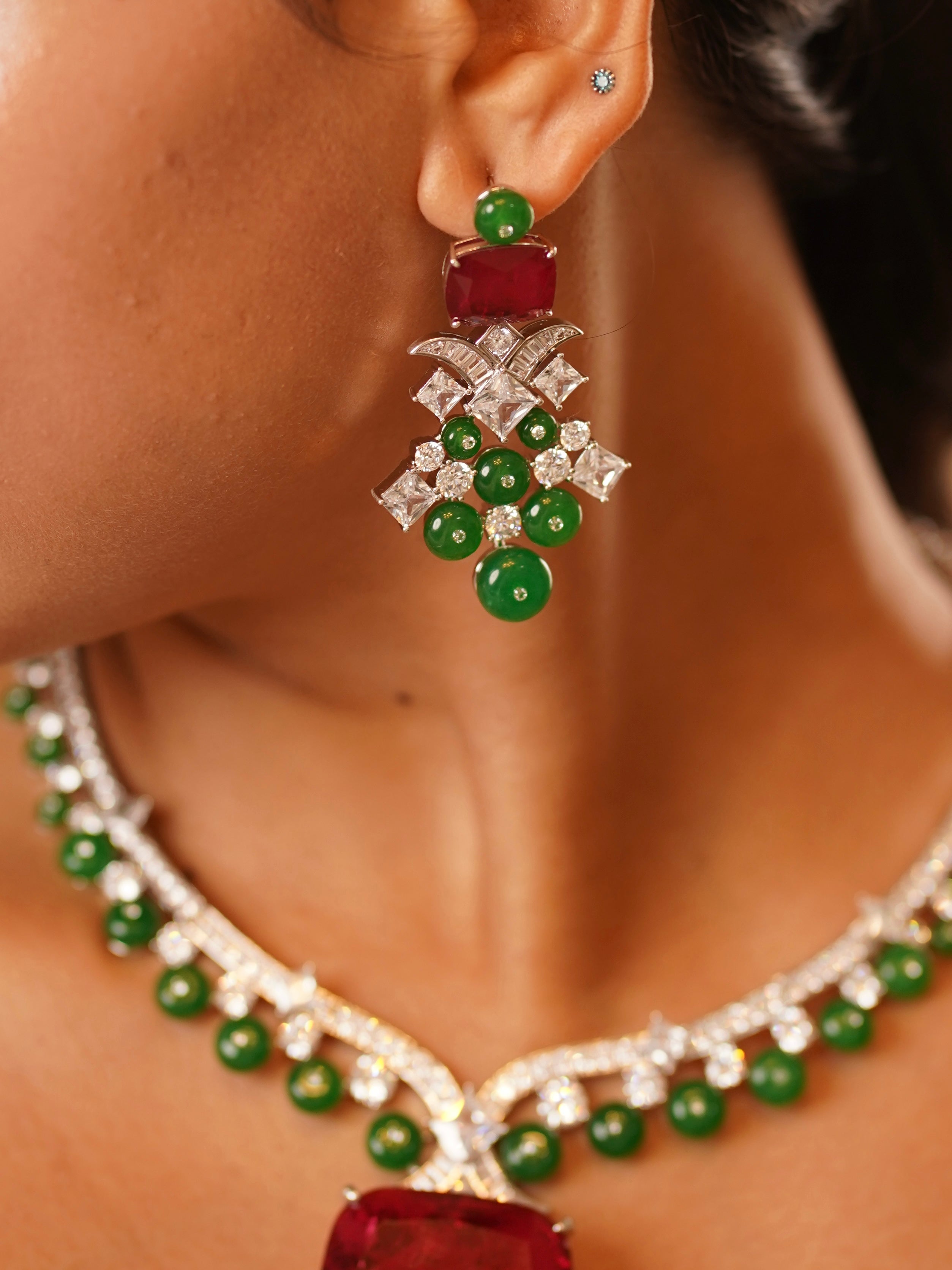 Angled view of ruby-emerald grandeur necklace with layered green and red stones