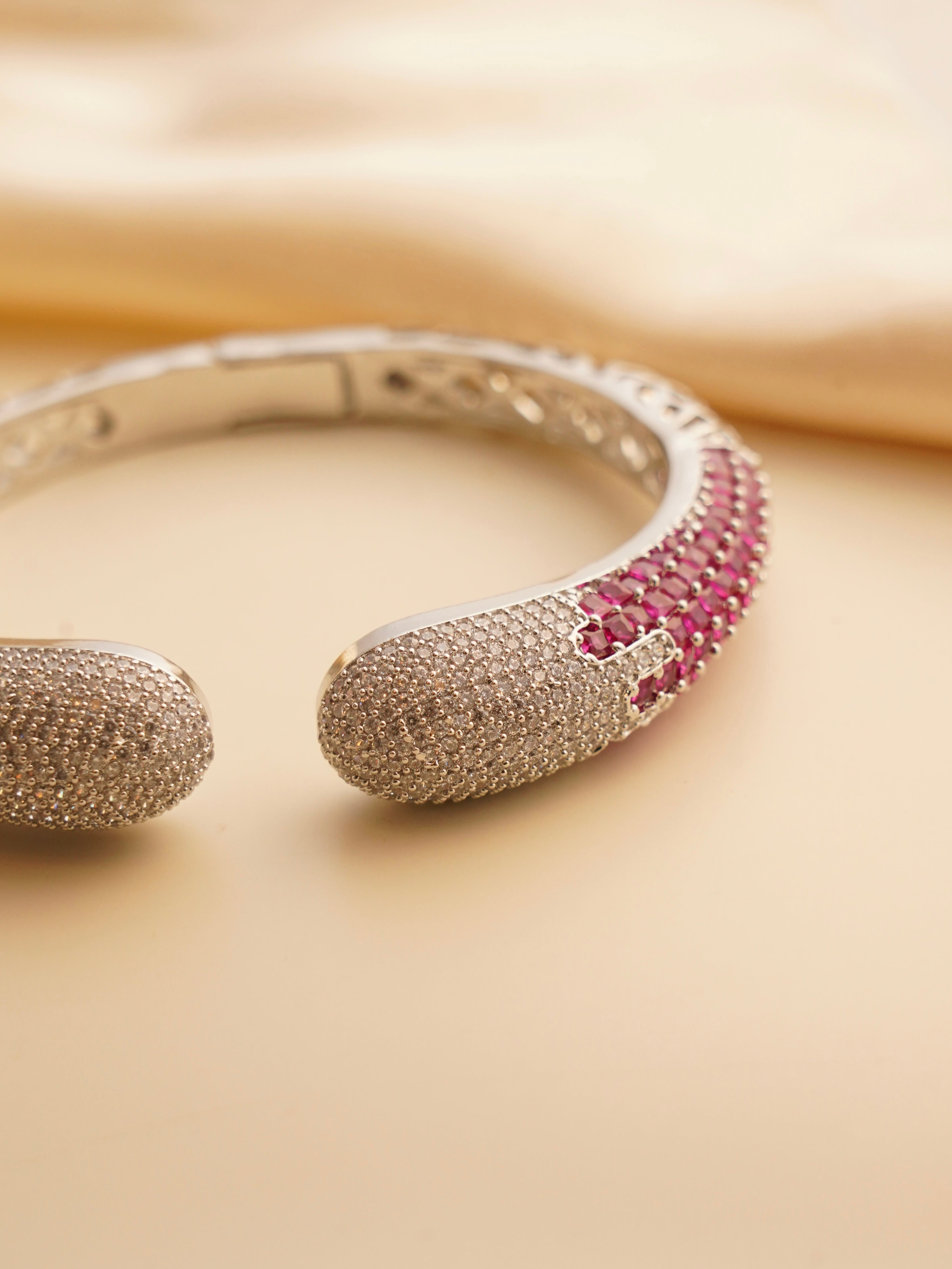 Openable designer bracelet with zircon stones set on gold-toned copper alloy in front view