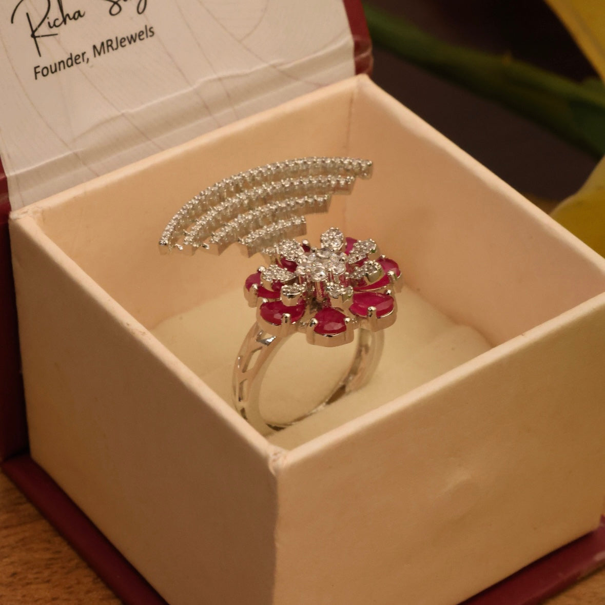 Floral statement ring with red stones and diamond arc in silver-tone metal
