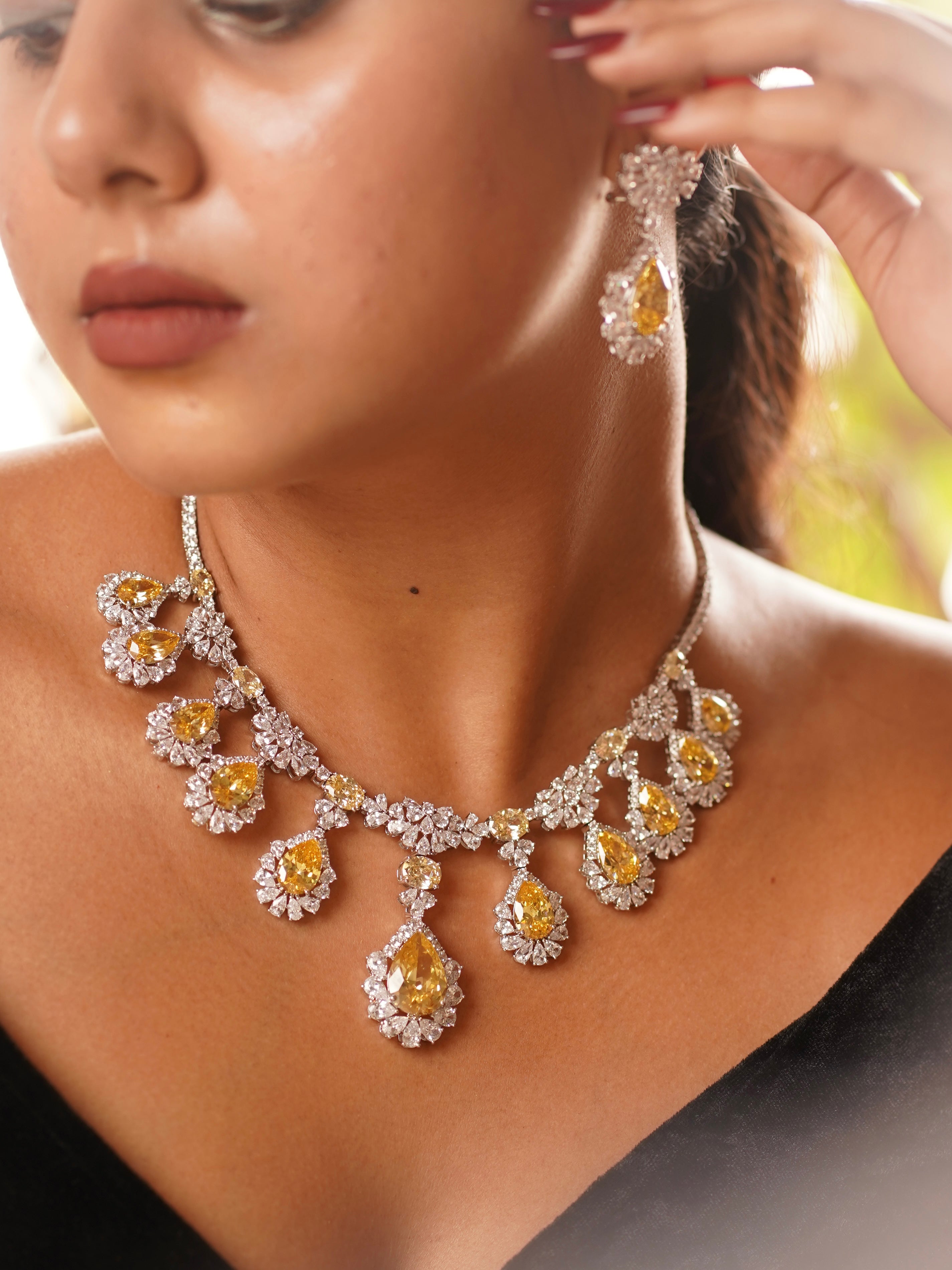 Angled view of citrine diamond necklace set featuring faceted citrine drops and polished finish