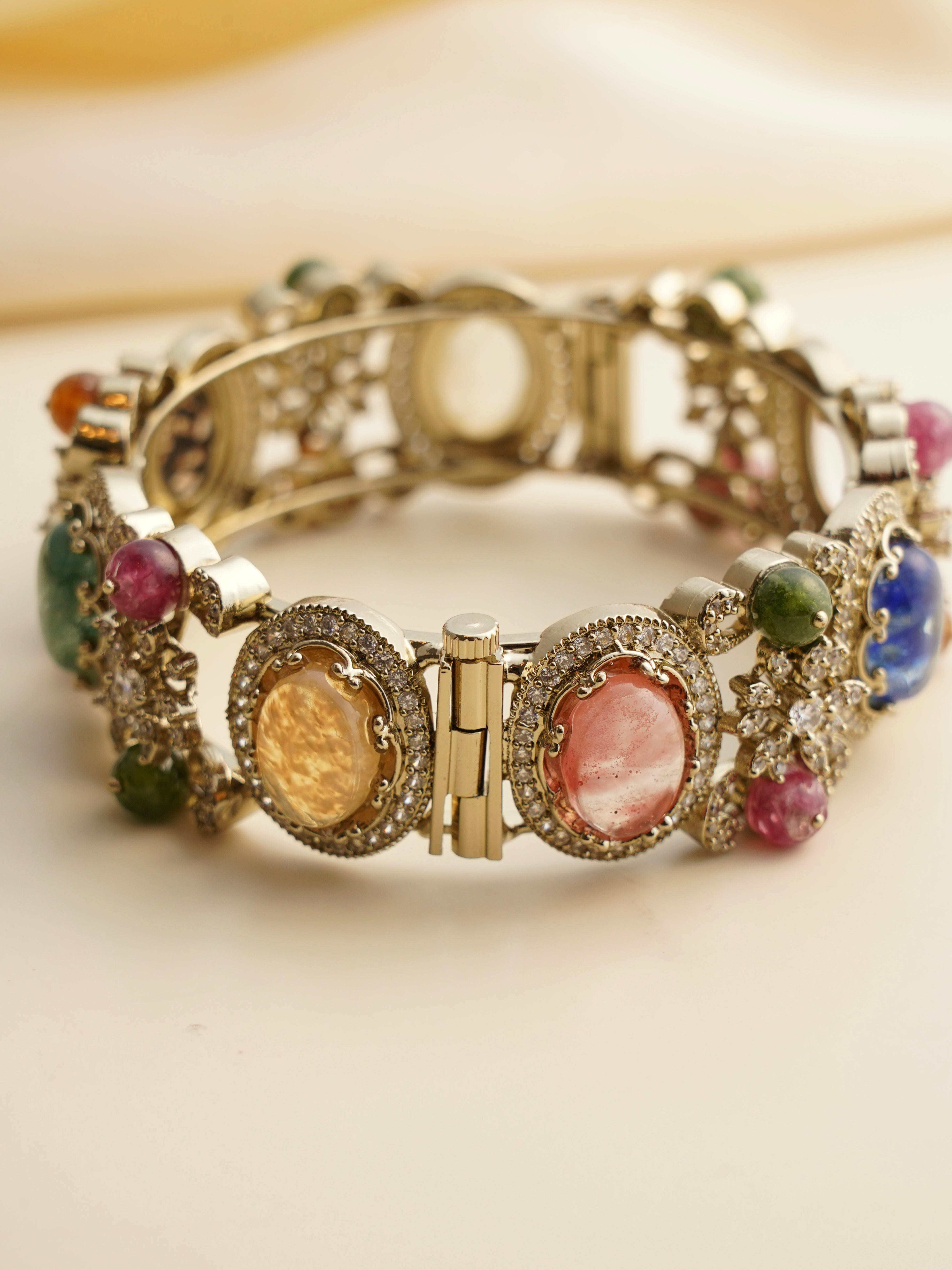 Close-up of gemstone-studded kada bangle with antique finish and hand-set floral detailing