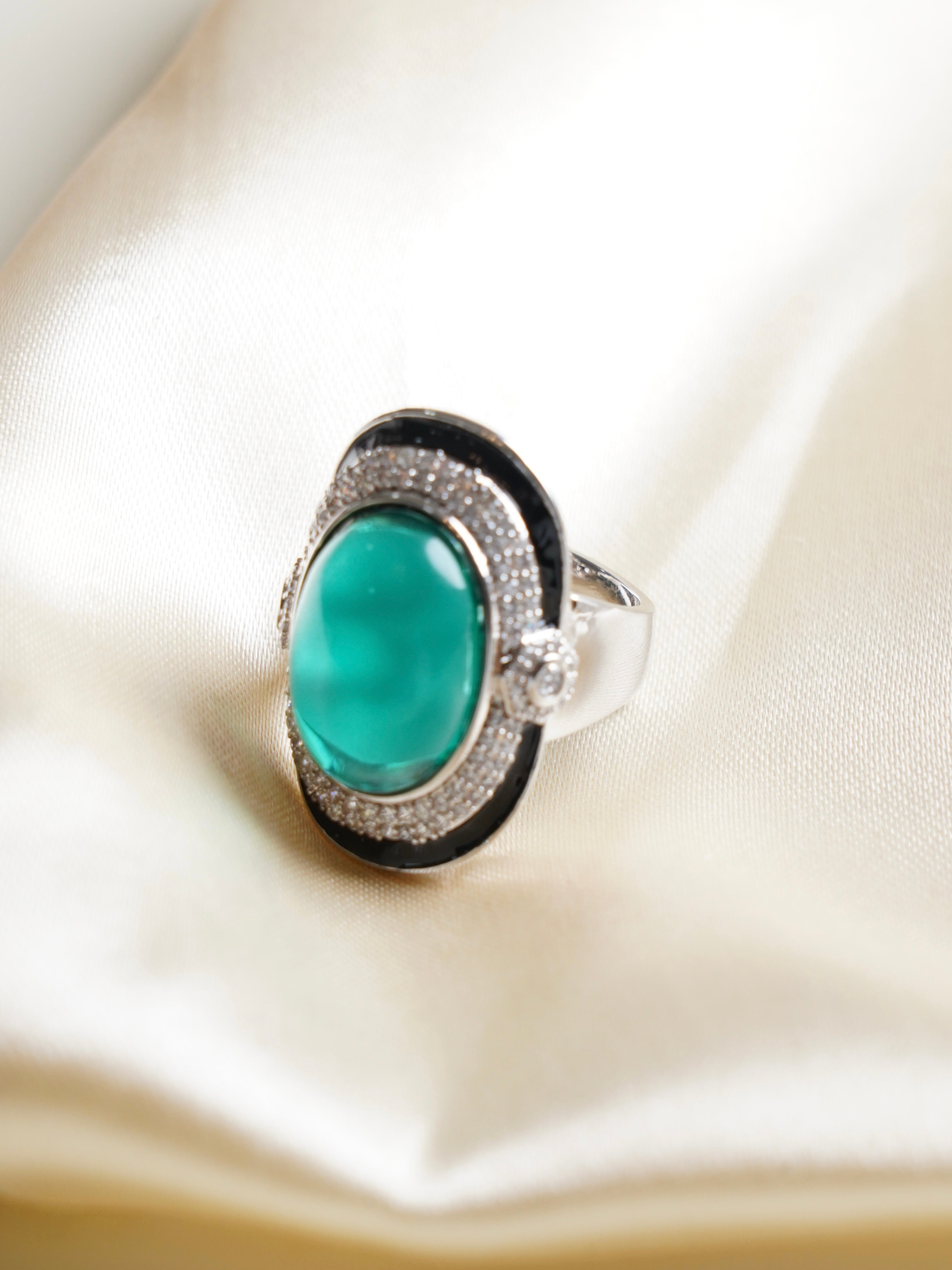 Emerald Mirage ring featuring a green cabochon centre stone, pavé zircon halo and black enamel border