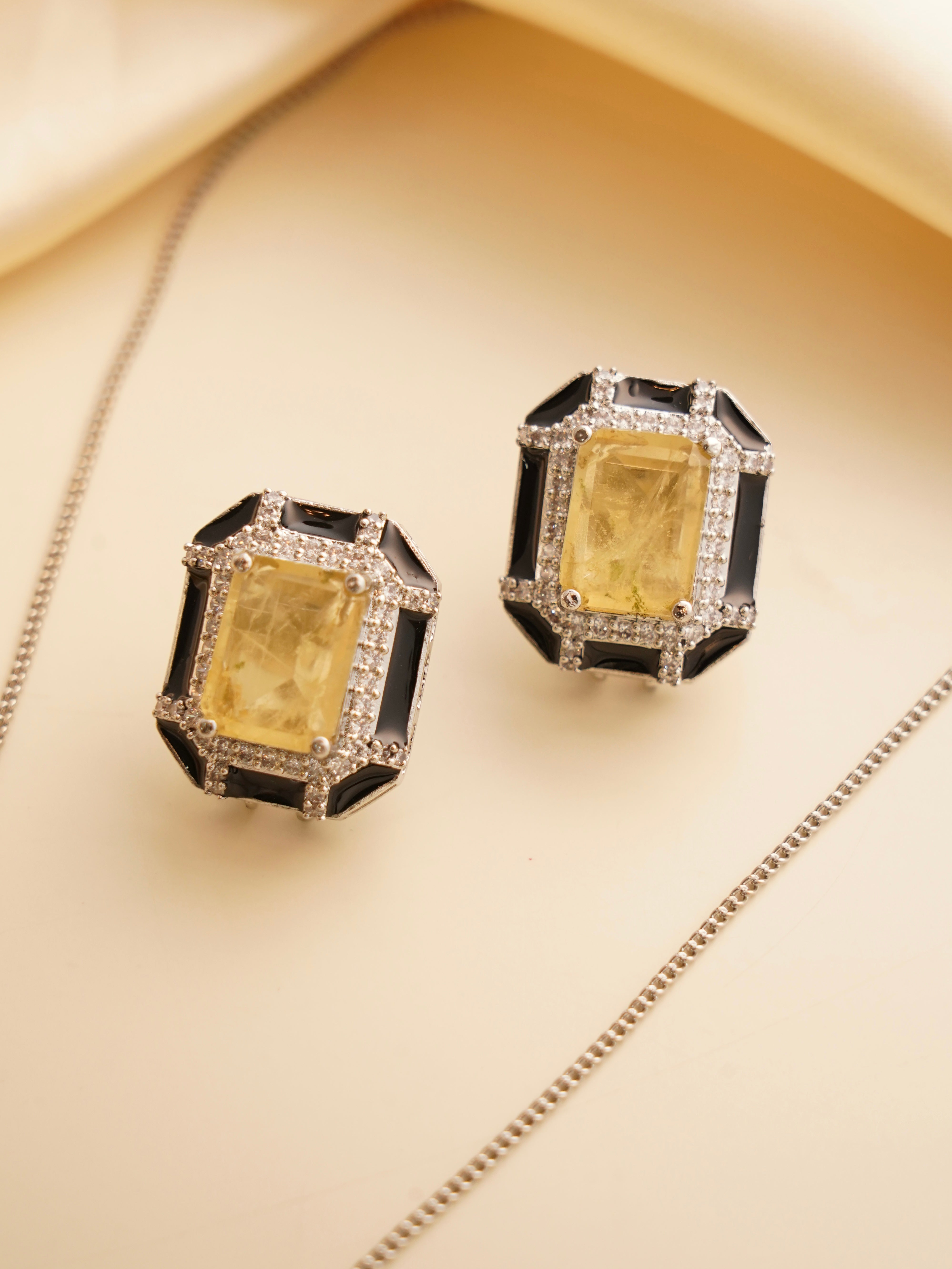 Zoomed-in shot of art deco set earrings with citrine-hued stones framed in enamel and studded with zircons