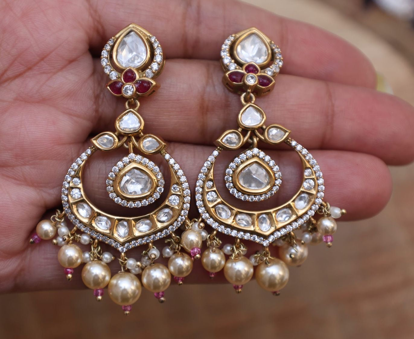 Angled shot of earrings showing profile curve, pearl hangings and stone setting