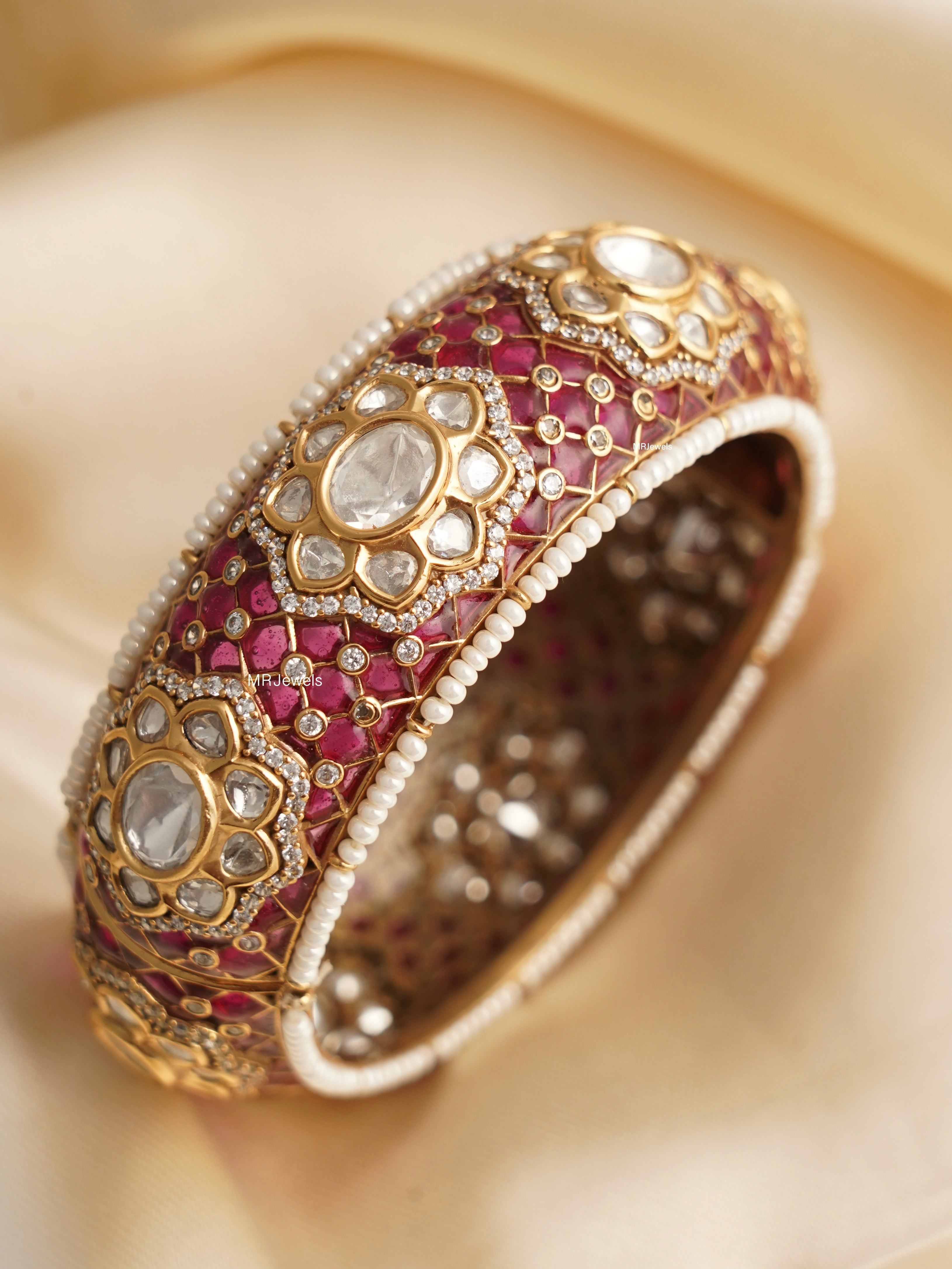 angled shot of handcrafted gold kada with meenakari and polki stonework