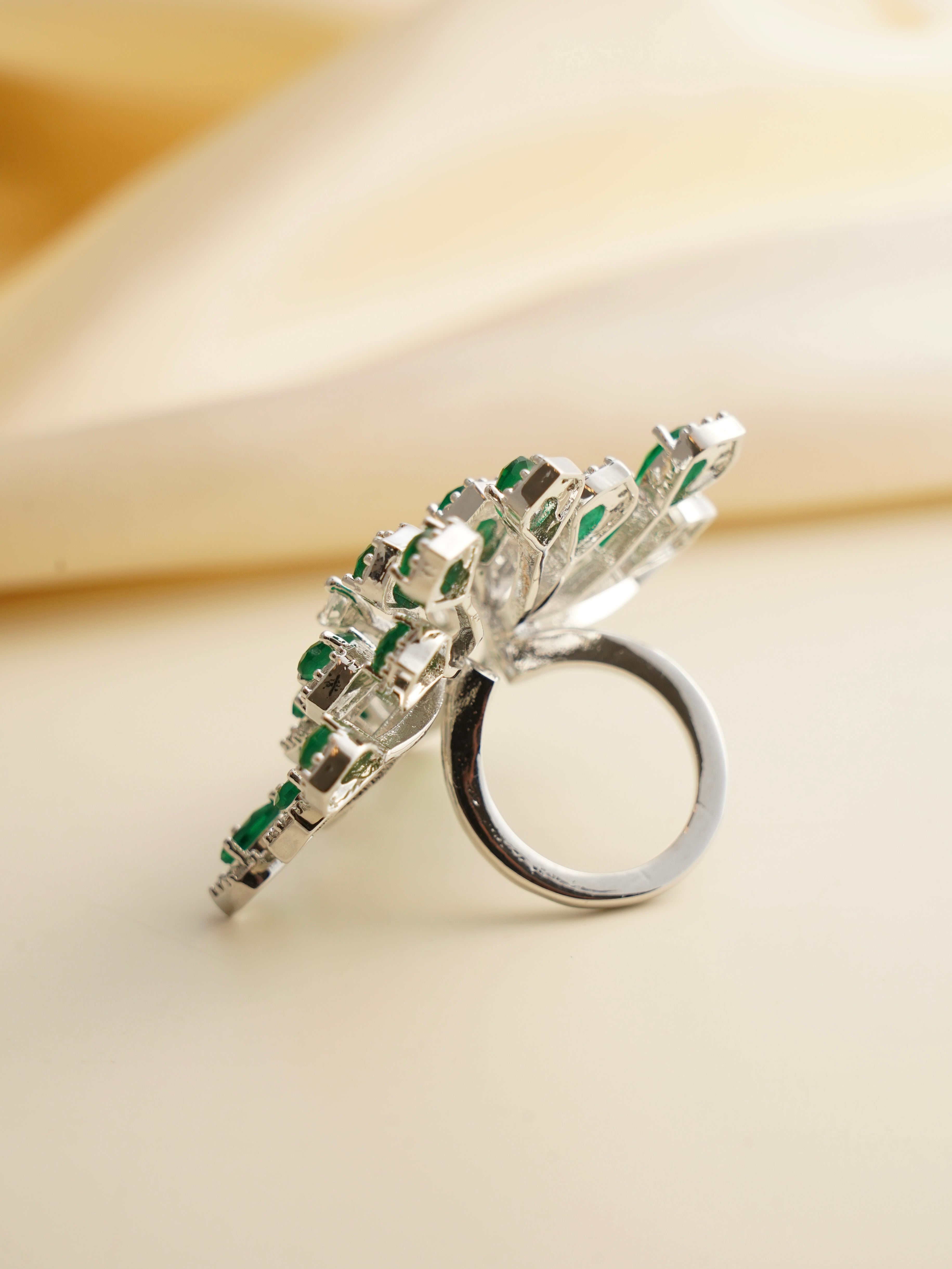 Angled shot of adjustable emerald cocktail ring showing layered gemstone arrangement
