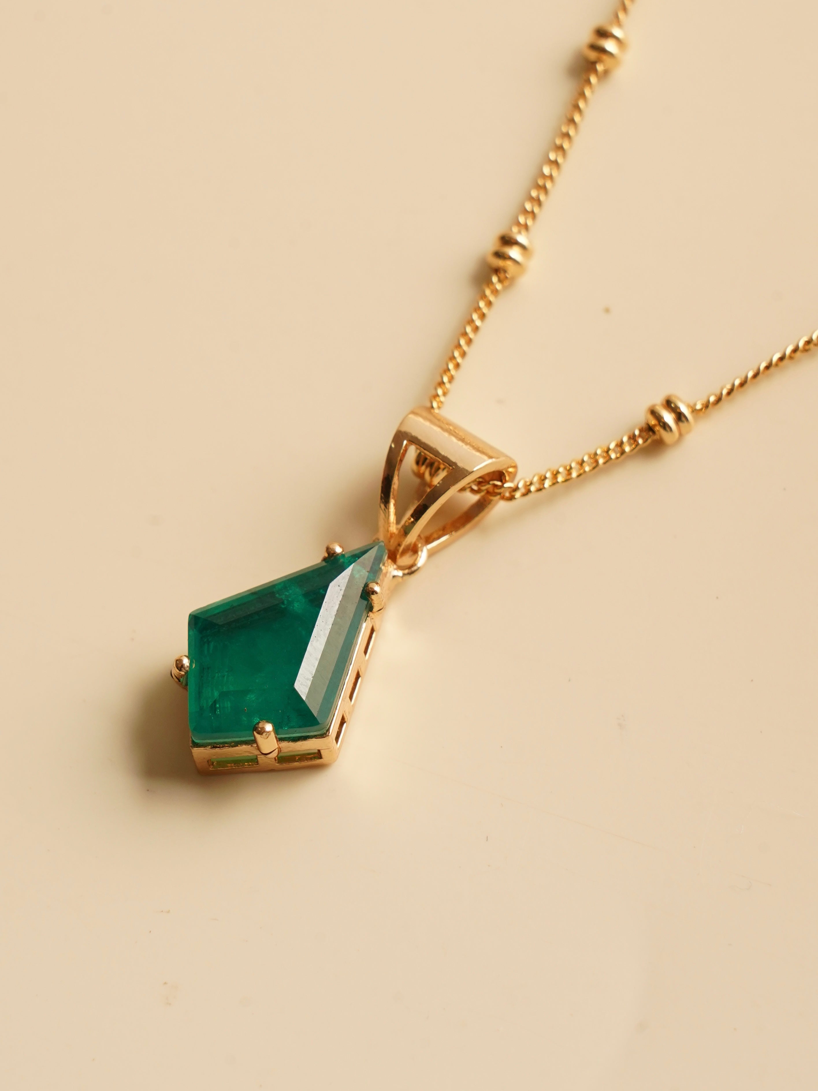 Close-up of ruby prism-cut pendant with beaded gold chain detailing