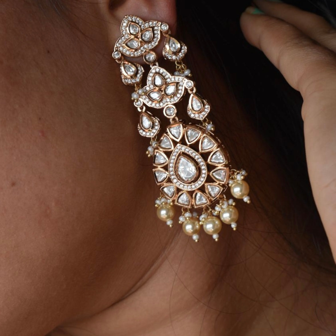 Pearl drop earrings with gold-tone finish and intricate crystal detailing in front view