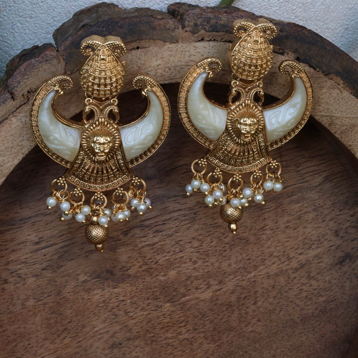 Designer tusk earrings with sculpted curve and gold-toned copper-brass finish