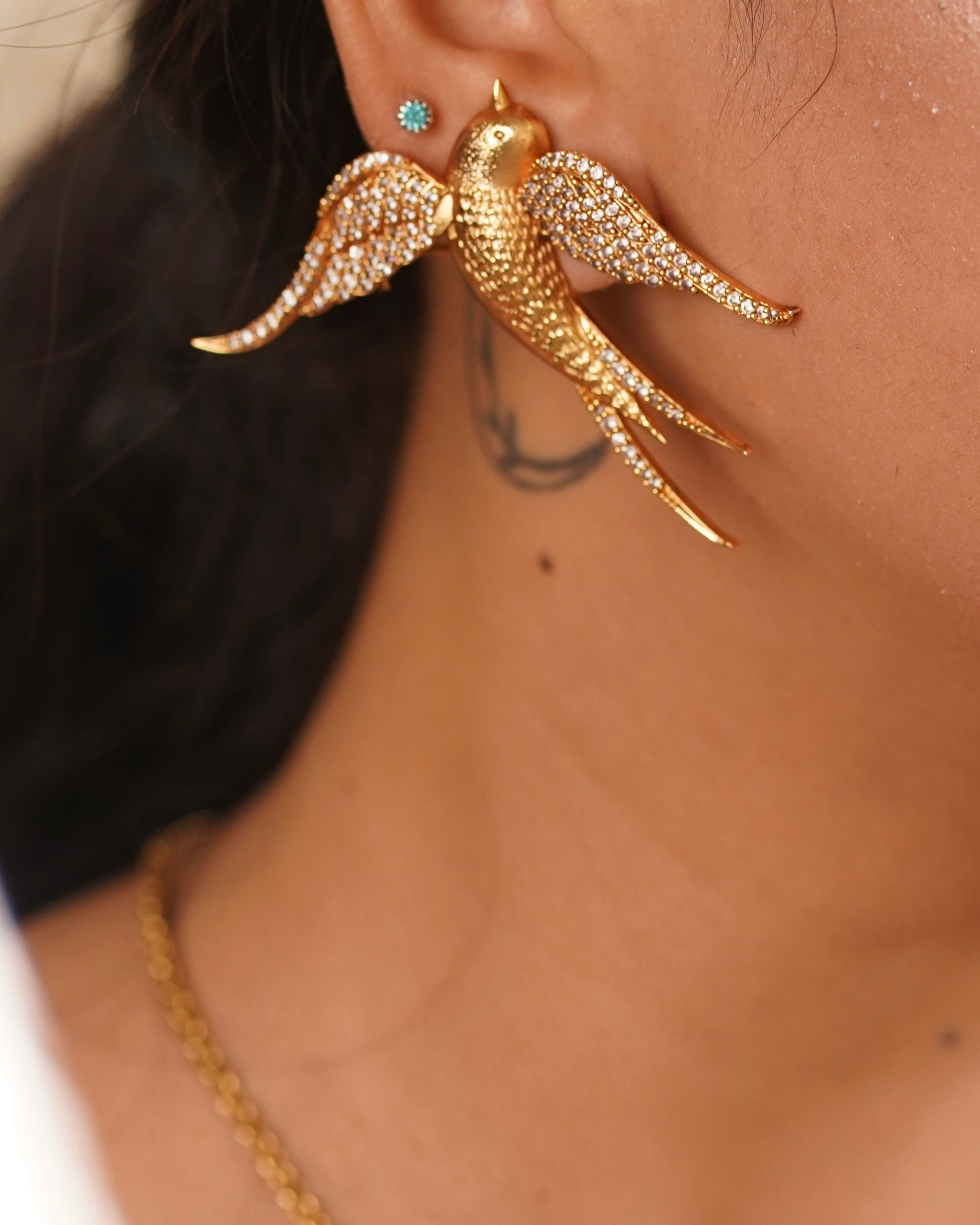 Close-up of bird-shaped pendant highlighting gold finish and stylized wing detailing