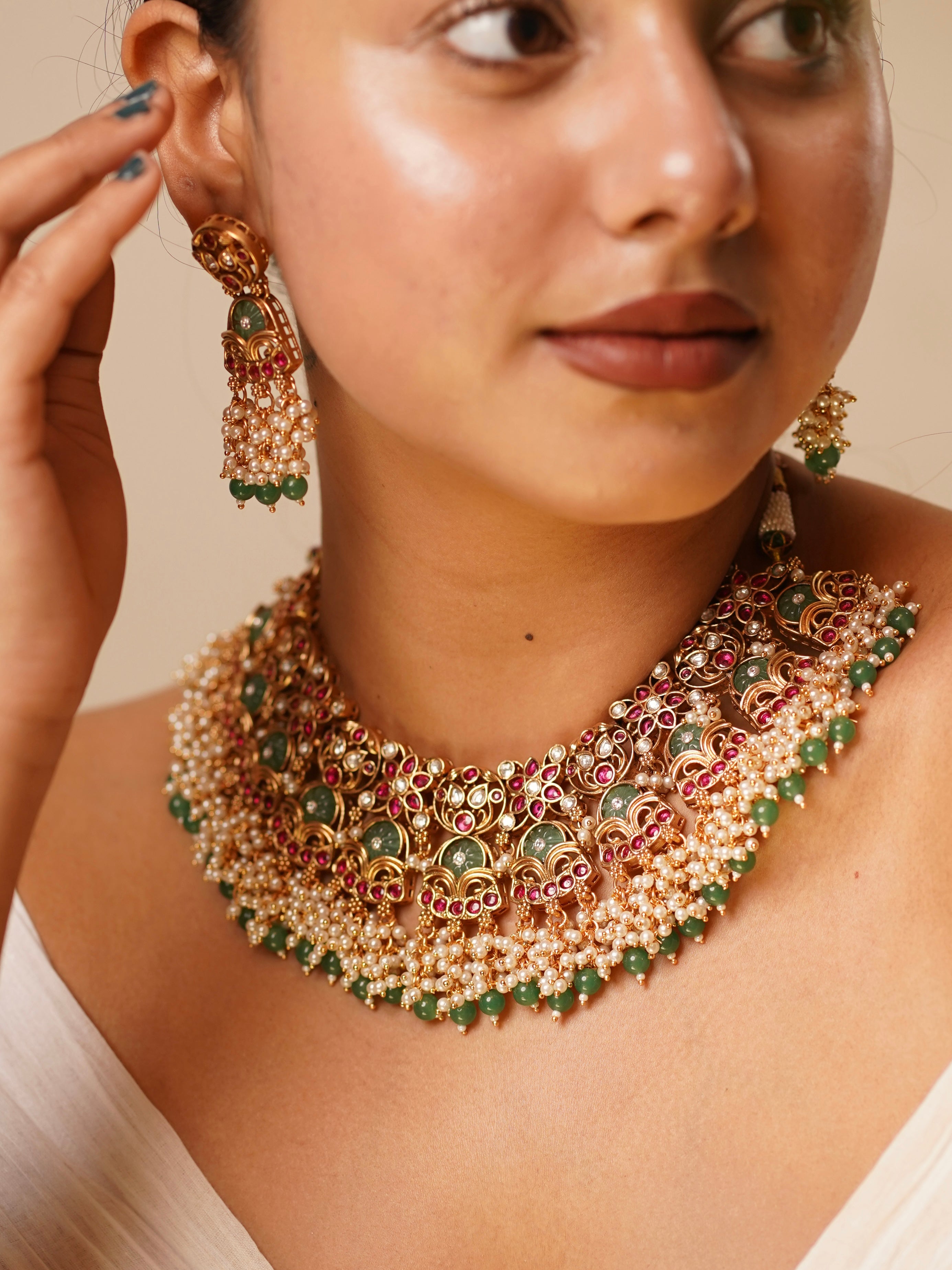 Close-up of temple choker earrings with ruby-toned detailing and antique gold finish