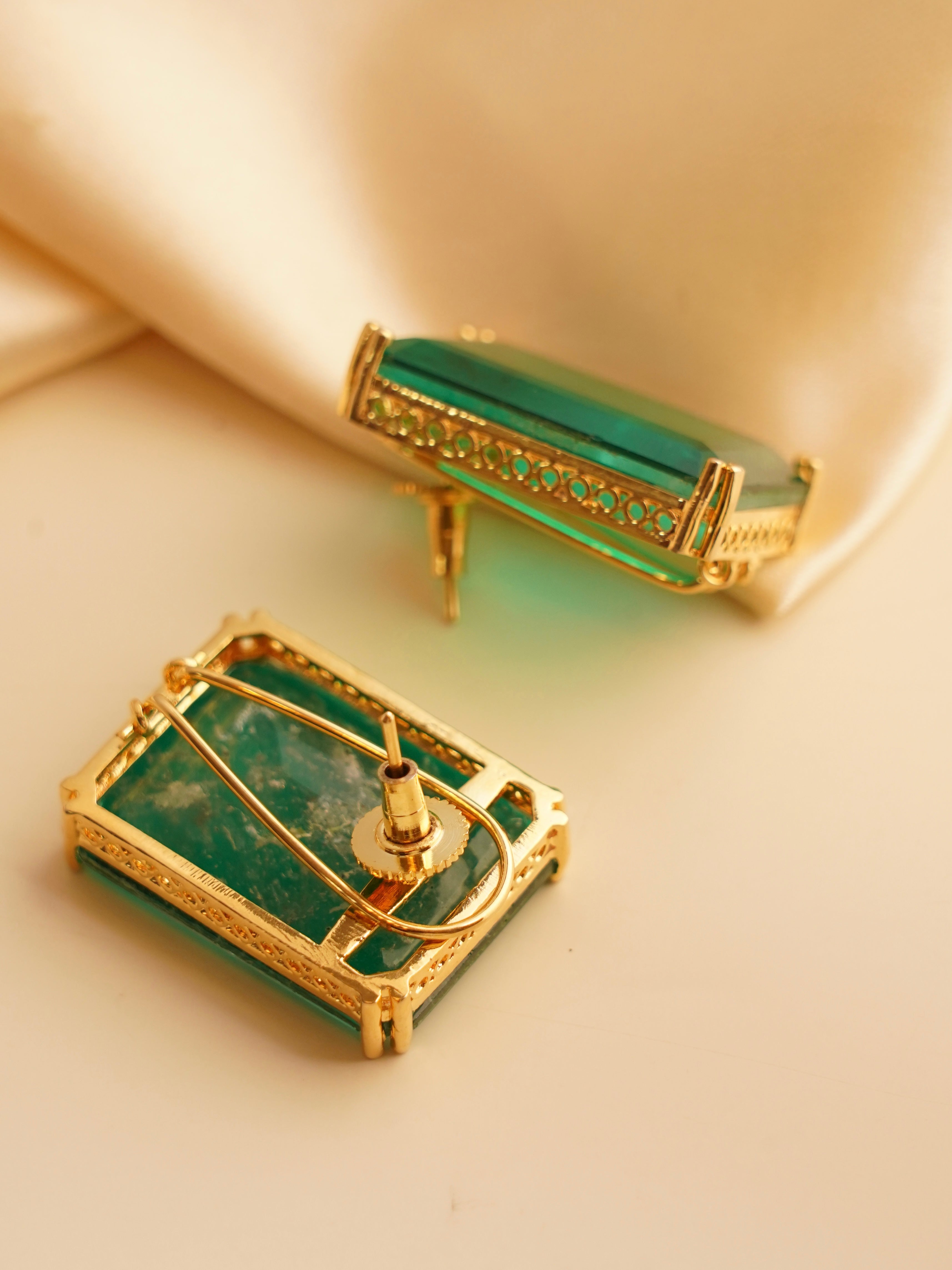 Angled view of statement earrings with vibrant rectangular stones and gold trim