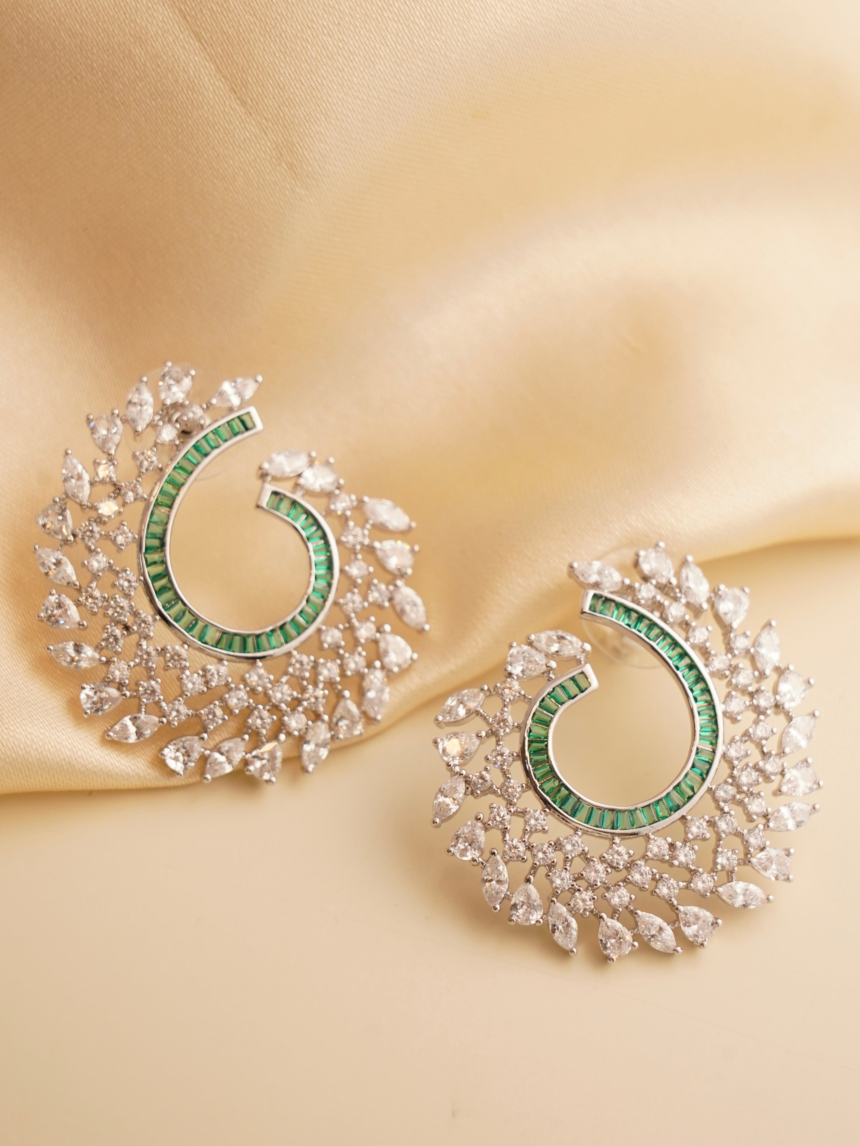 Close-up of sculptural swirl earrings in vibrant jewel tones with a high-shine finish