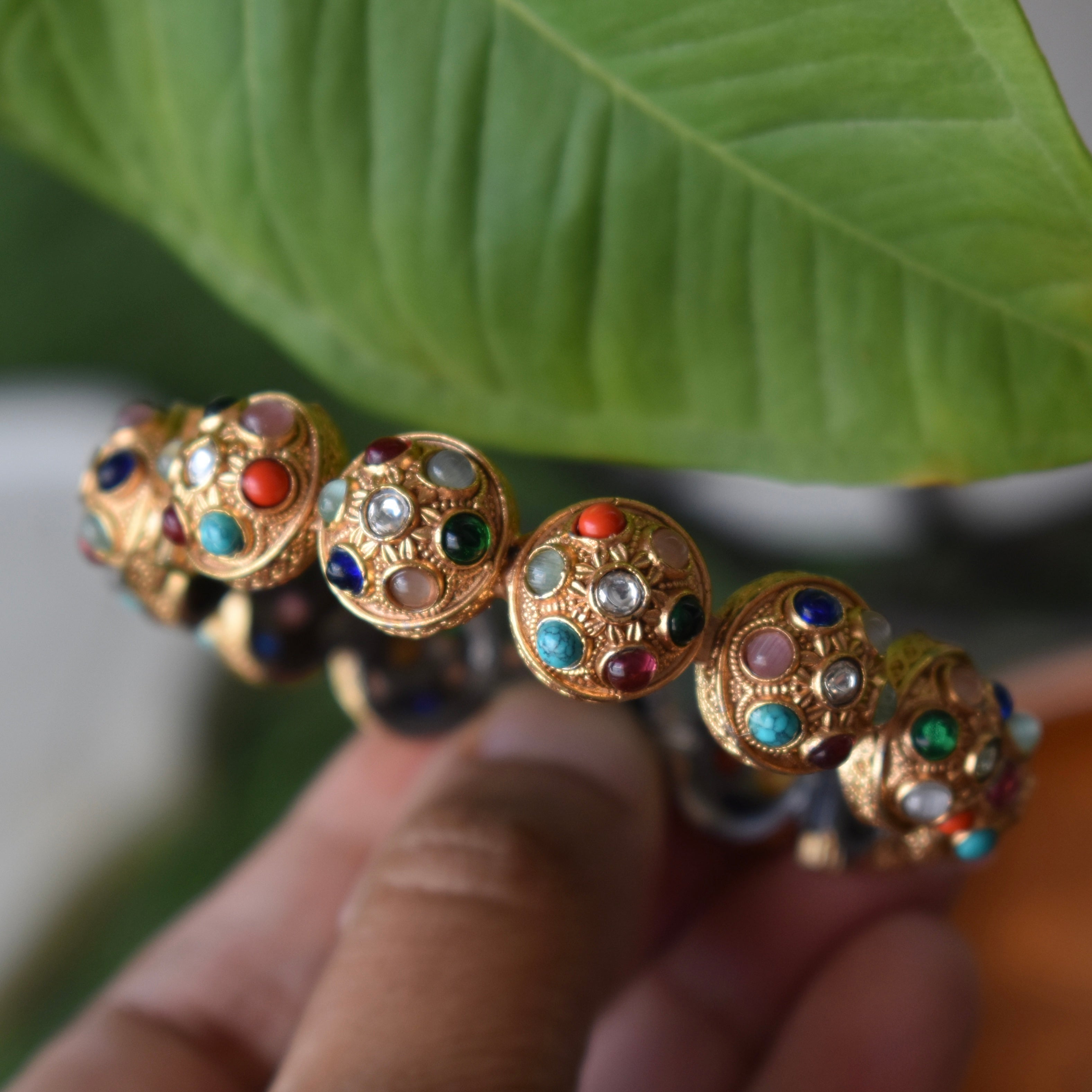 Side angle of openable Navratna bangle with vibrant stones and detailed etching