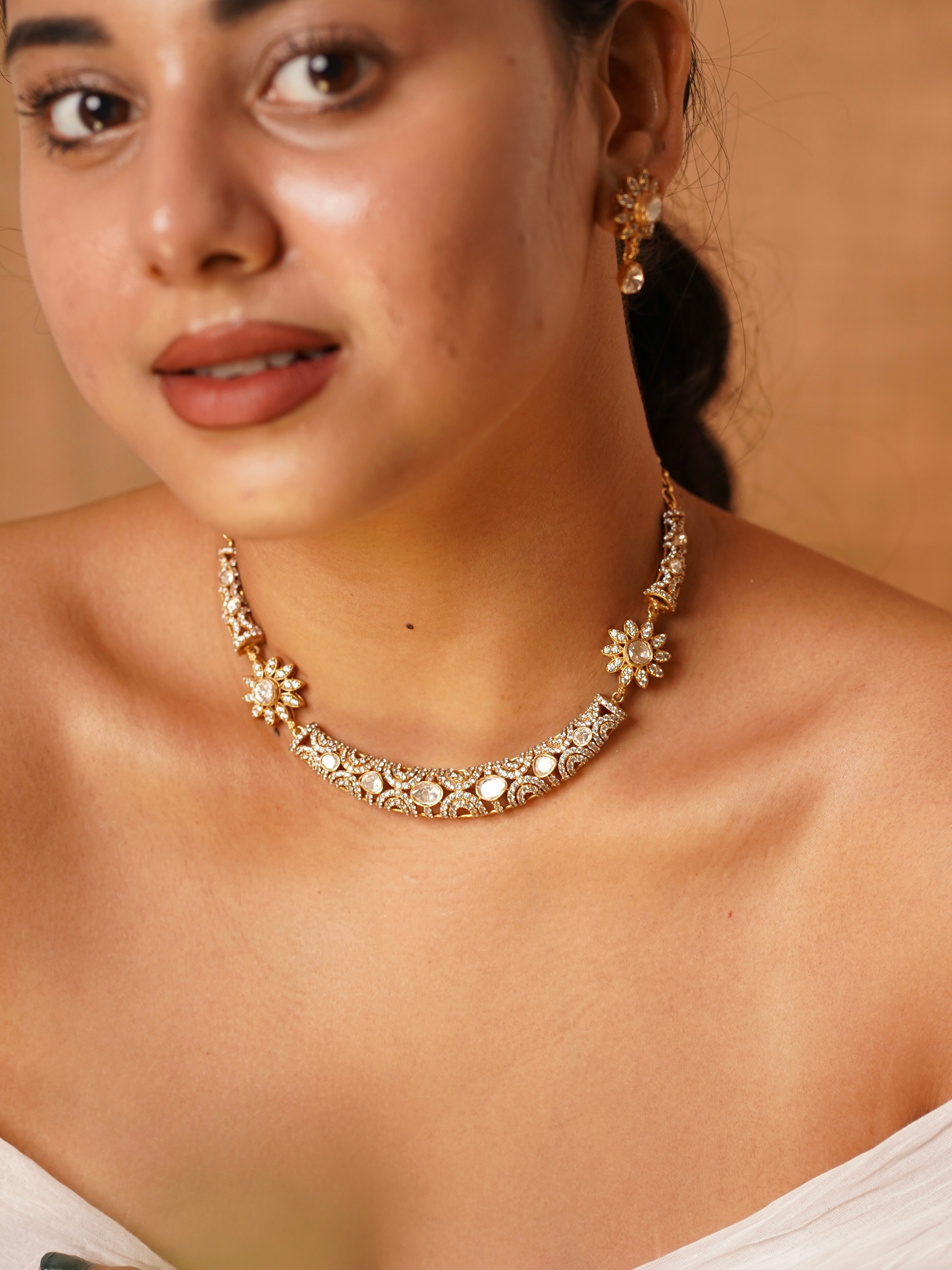 Model wearing Aarohi floral kundan choker set with antique gold floral motifs, kundan stones and matching earrings