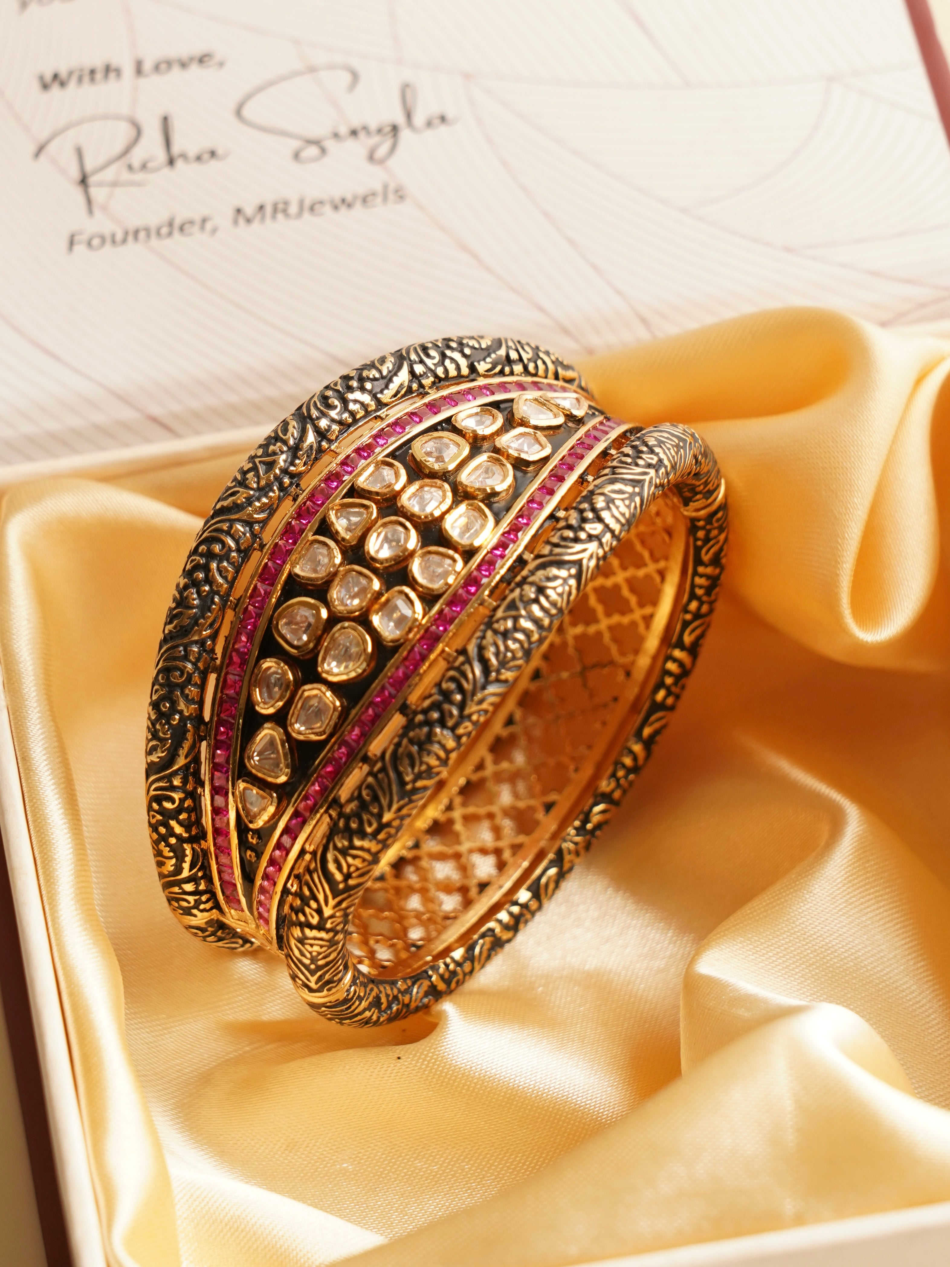 Close-up of vintage-inspired gold bangle featuring ruby stones and polki diamonds