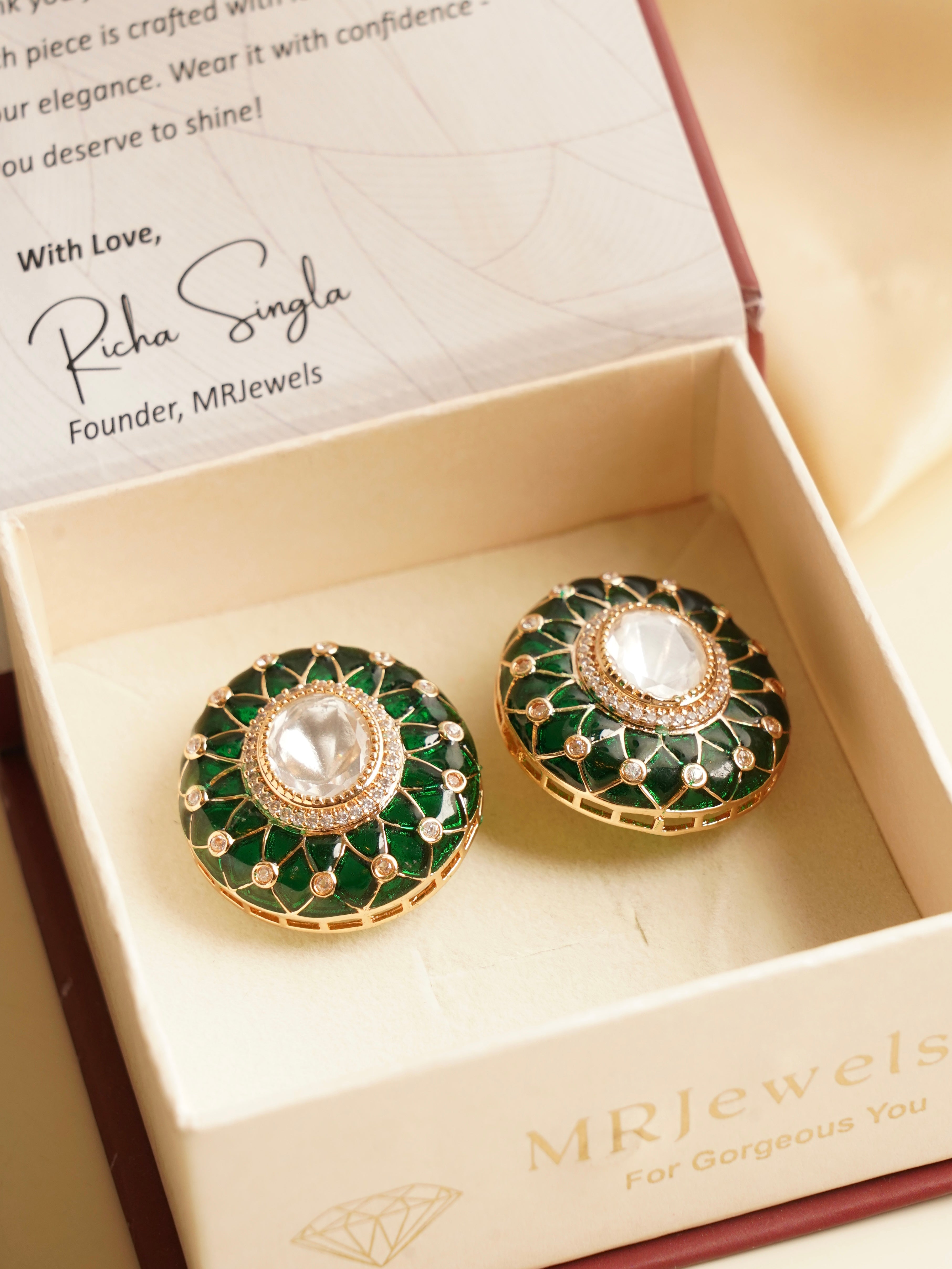 Side view of gold-toned designer earrings with floral motif and enamel highlights