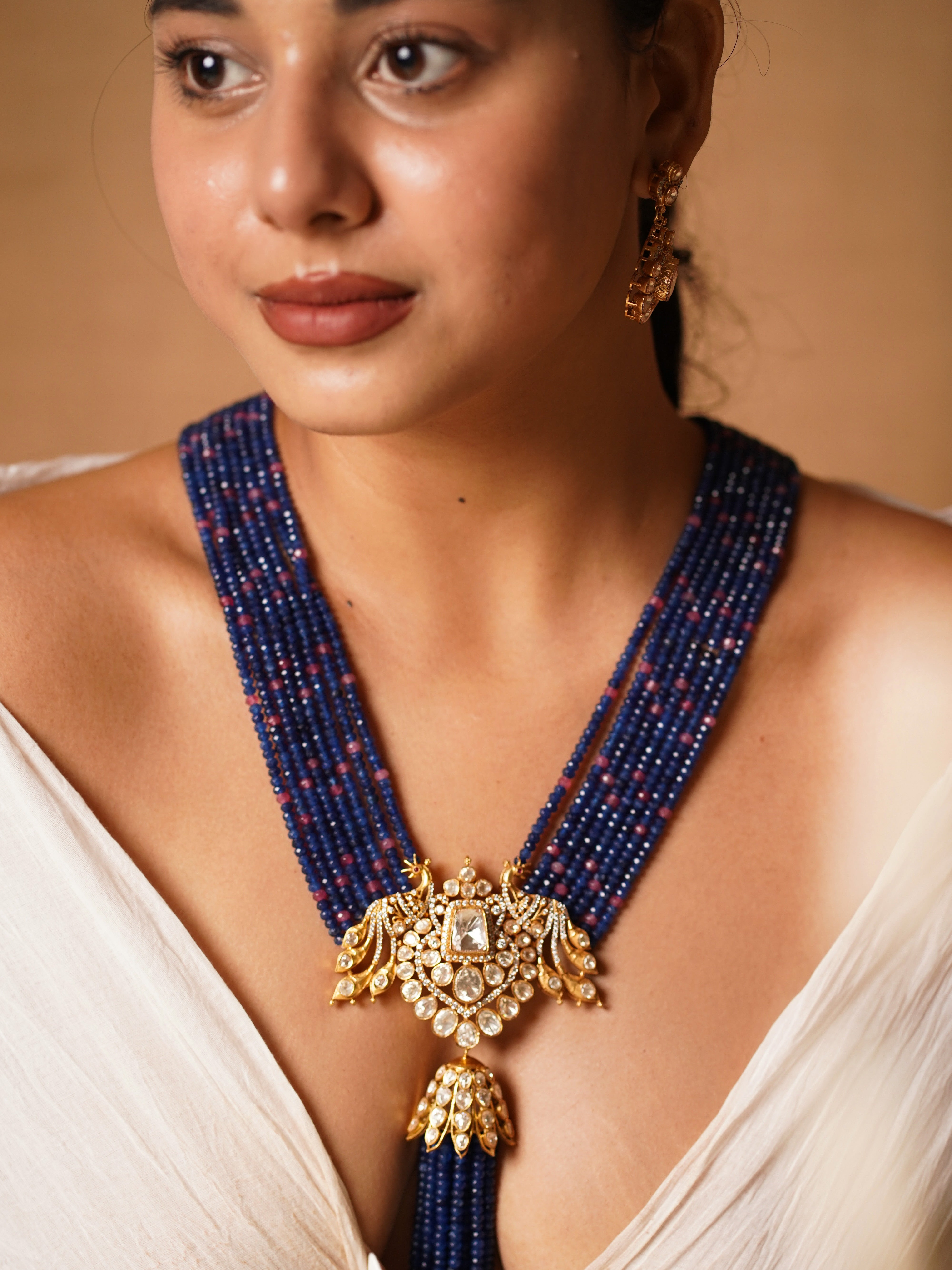 Side view of peacock kundan necklace with royal blue and emerald accents