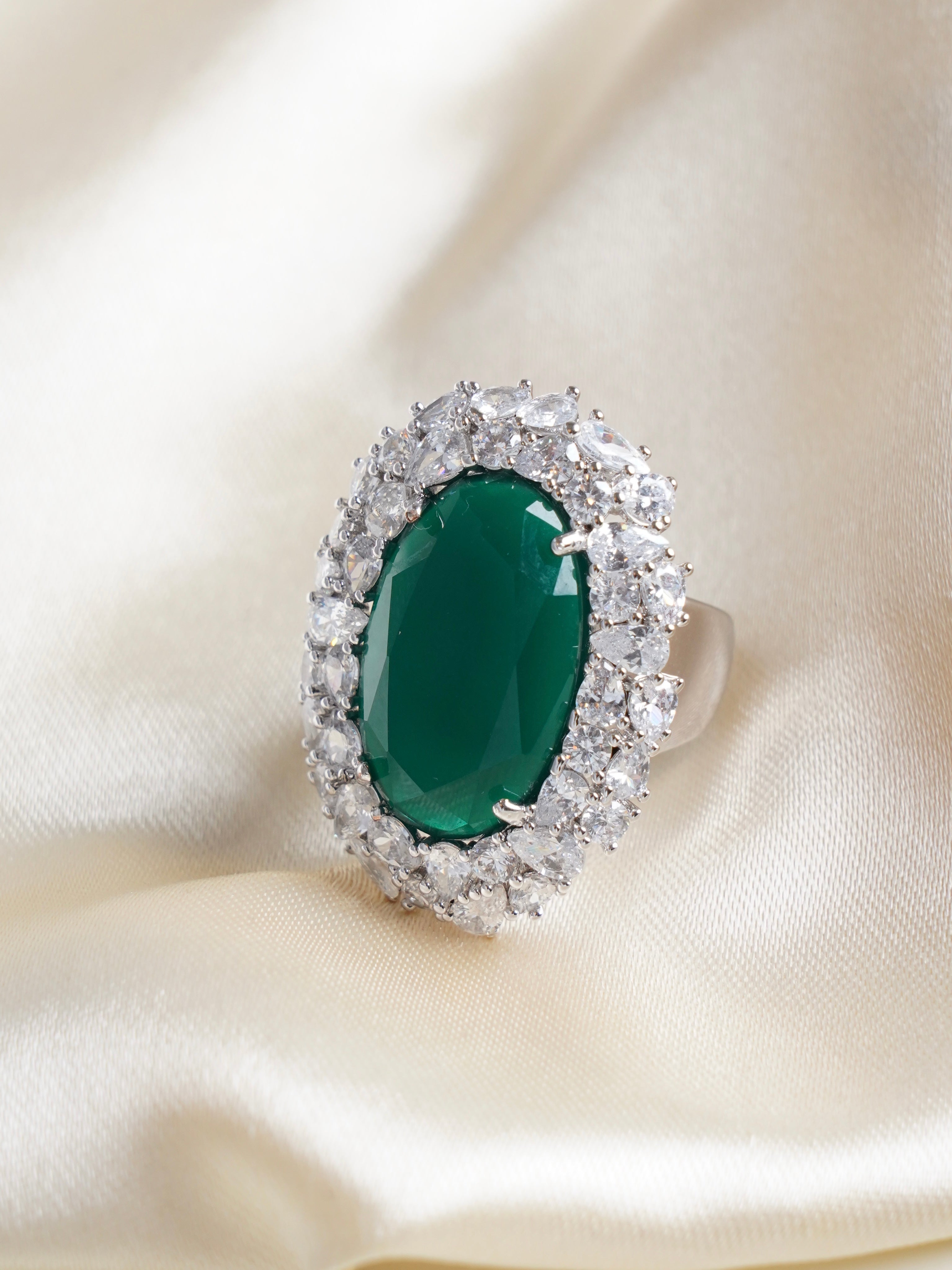 Side view of adjustable emerald ring with high-shine silver band and faceted green centre stone
