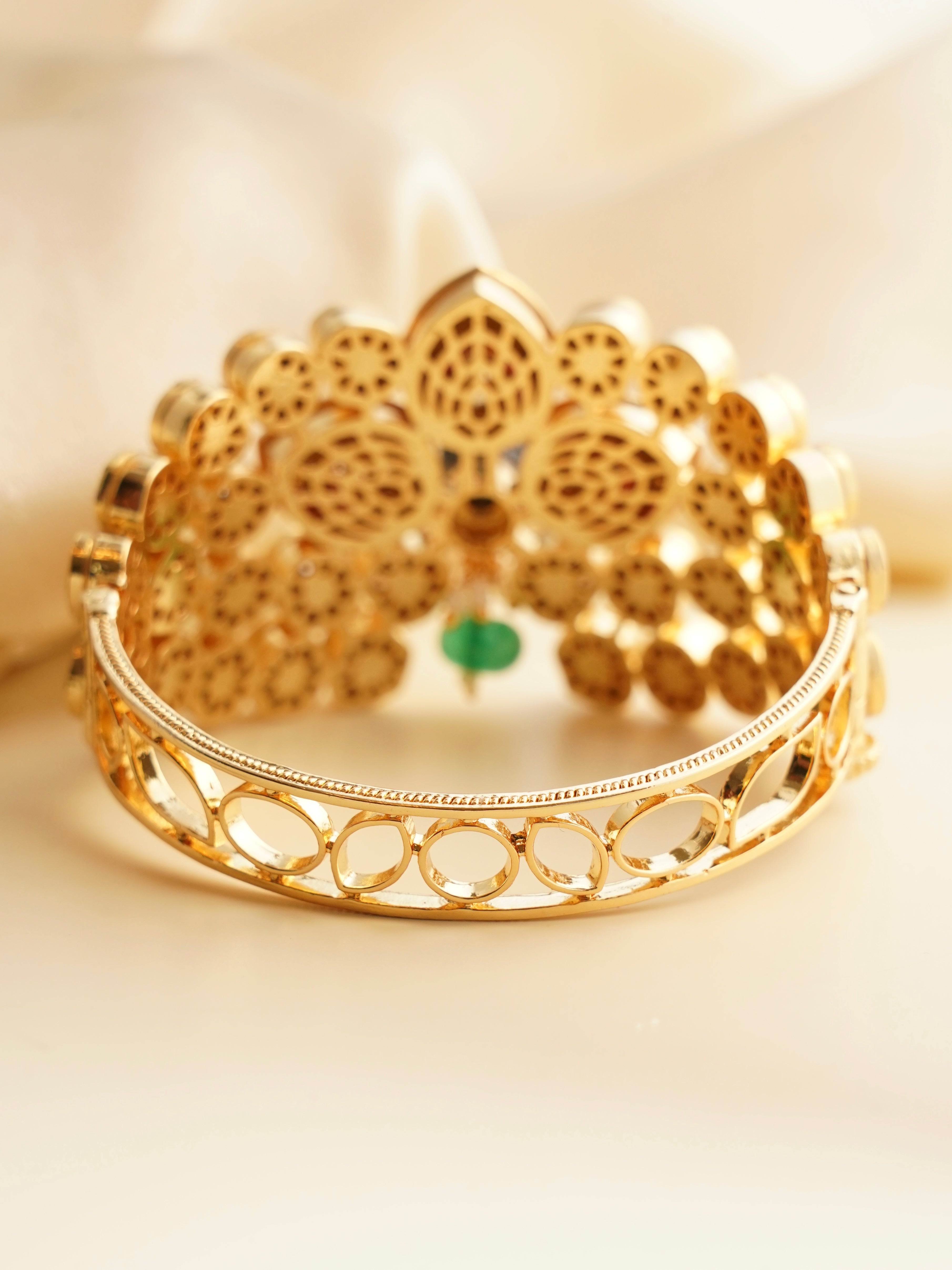 detailed view of peacock-themed bracelet in gold with shimmering embellishments