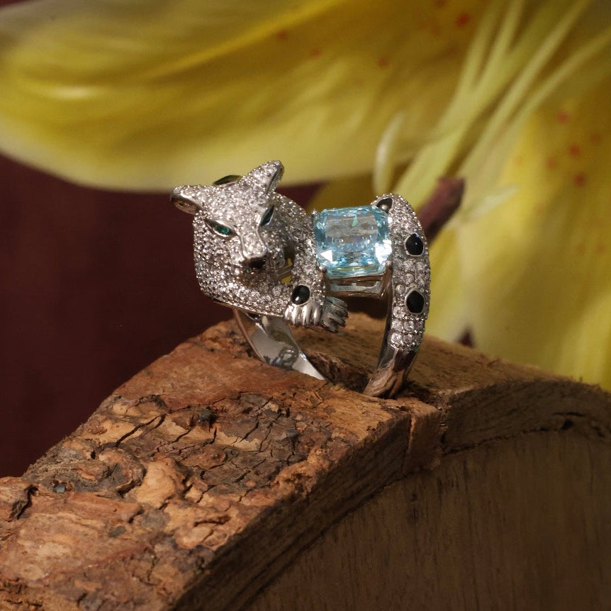 Side view of topaz ring with emerald-eyed panther and detailed silver finish