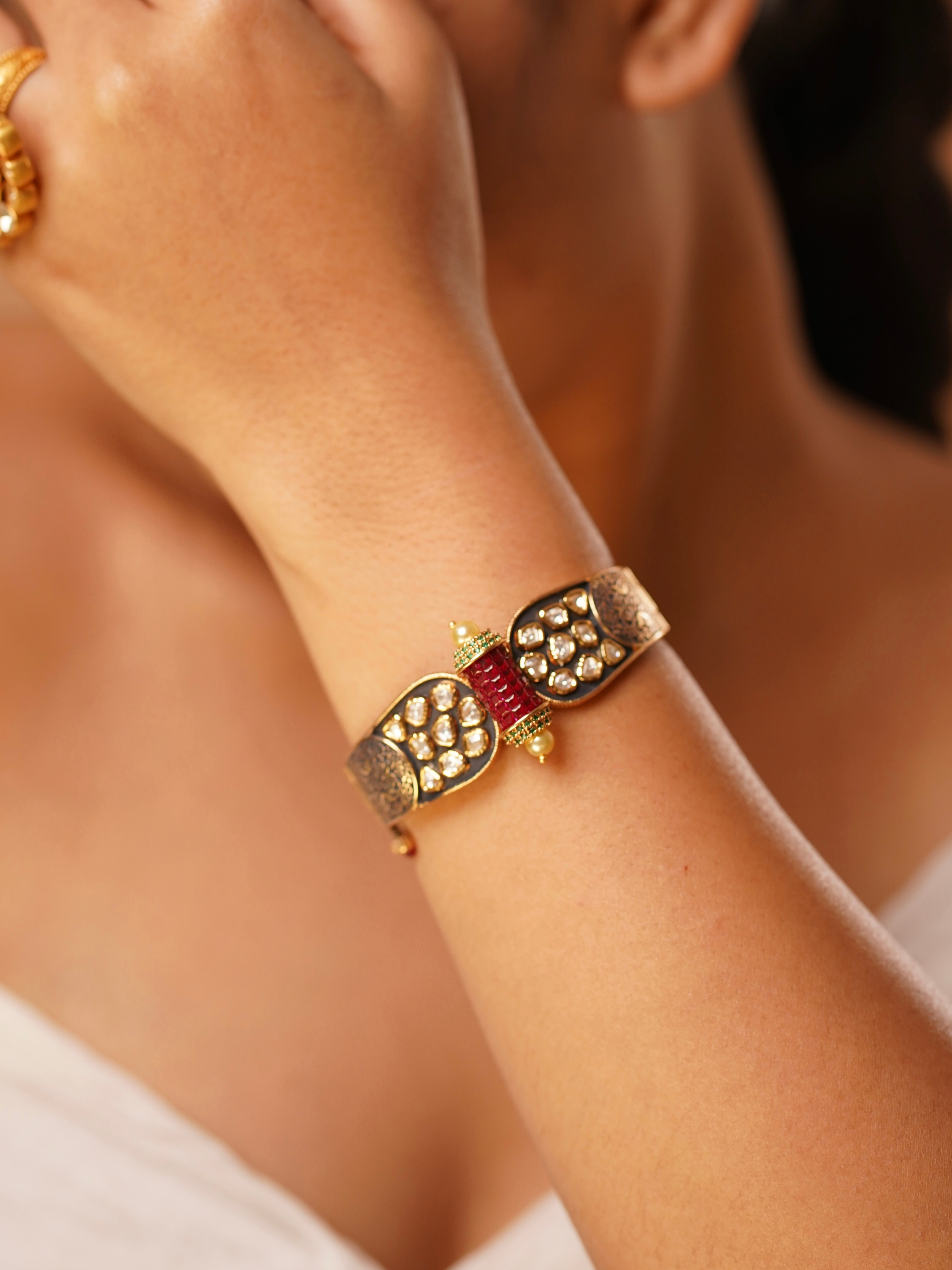 Close-up of designer gold bracelet with heritage enamel and sparkling Kundan embellishments