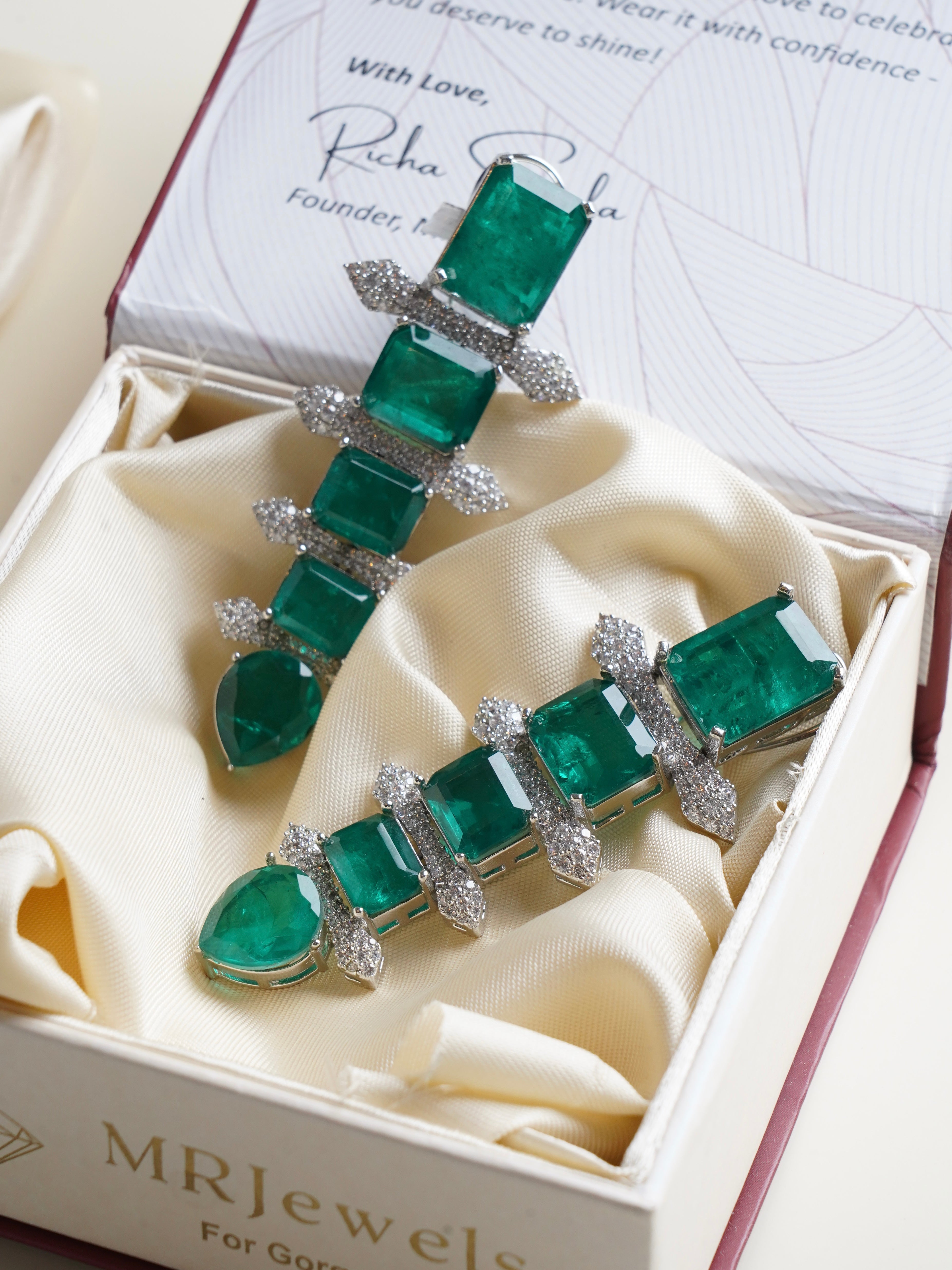 Side profile of emerald statement earrings featuring emerald-cut stones and bold drop silhouette