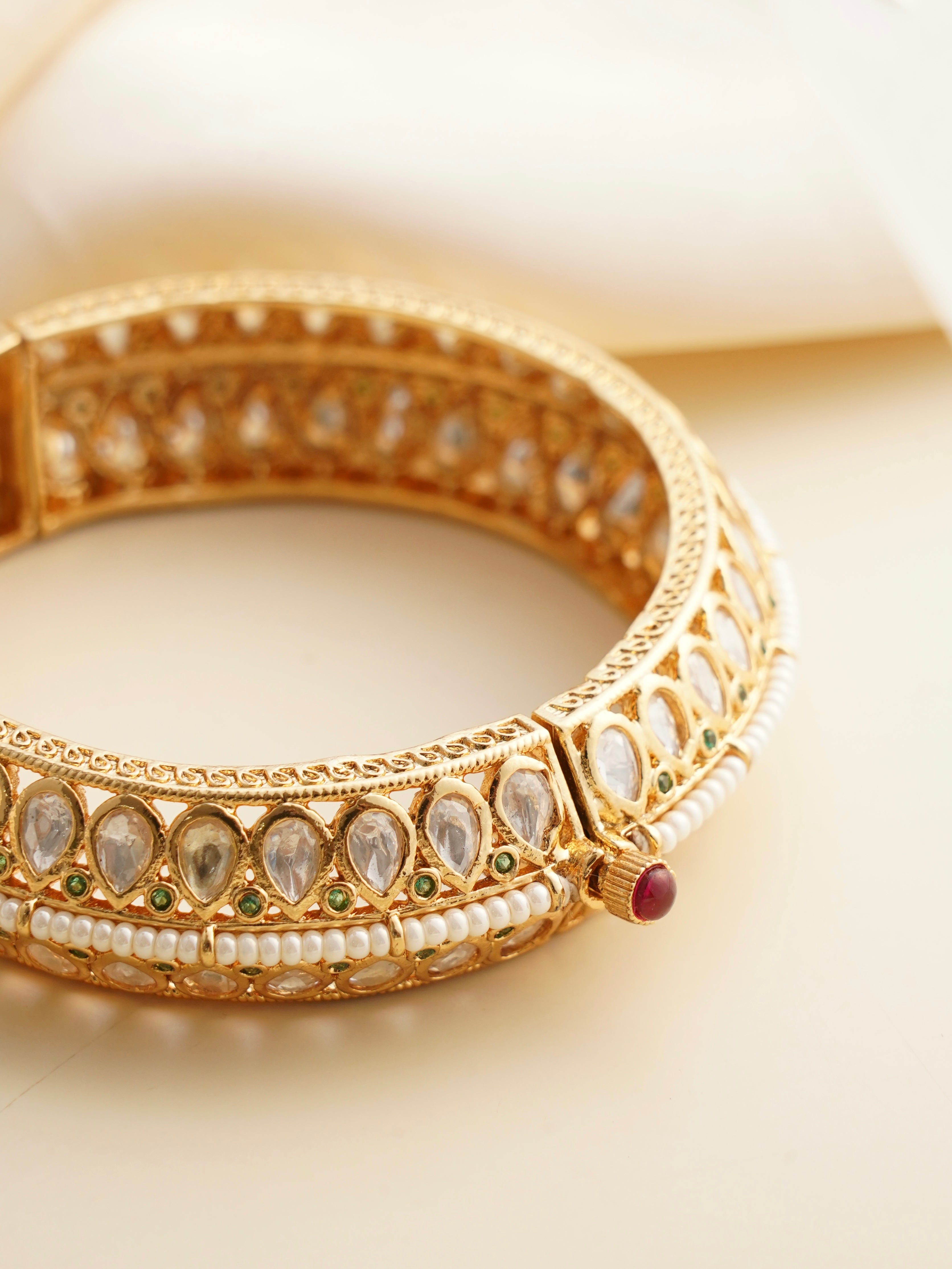 Side view of openable kundan bangle with ruby enamel screw clasp and polki-style stones