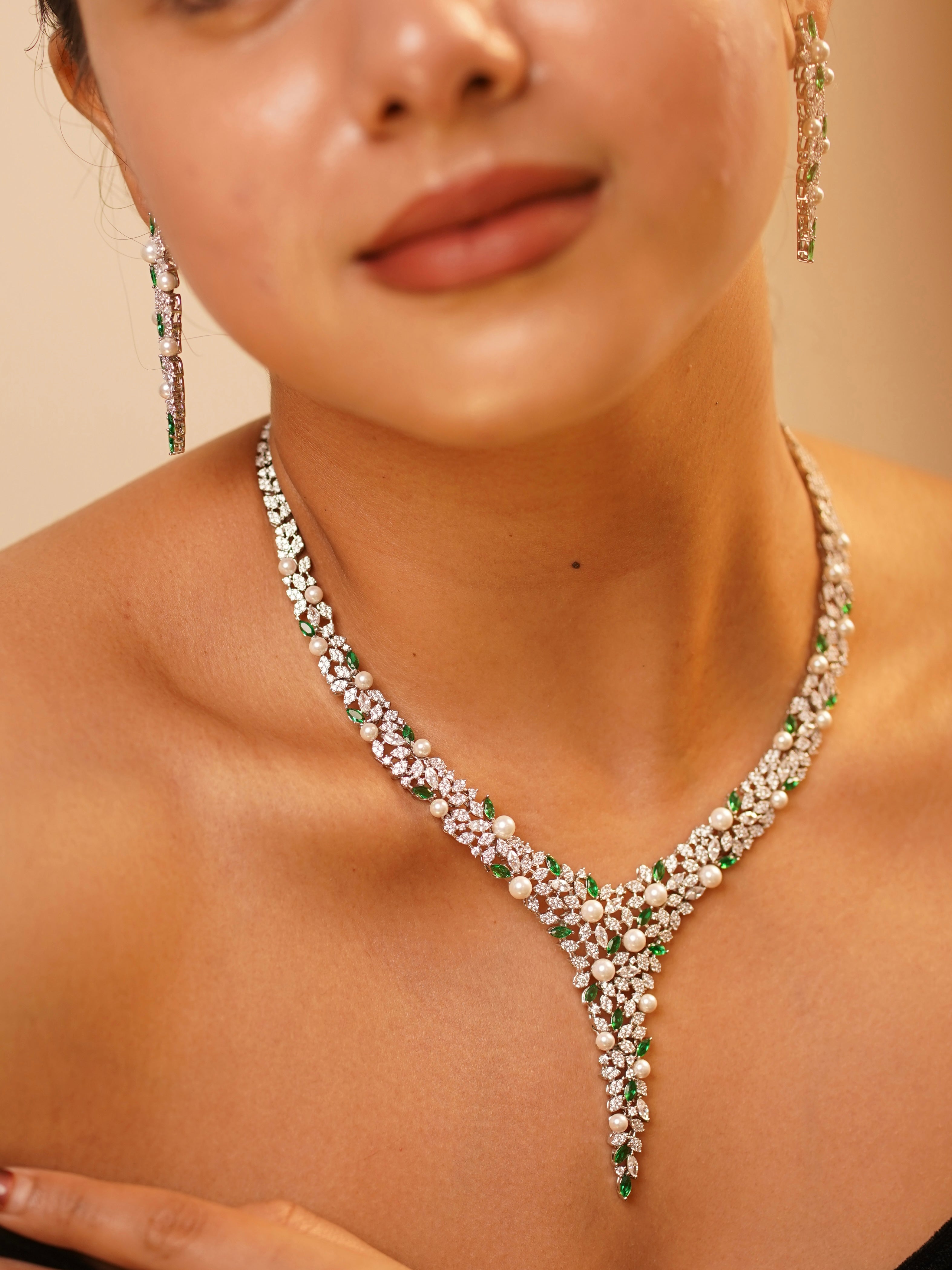 V-shaped necklace set with diamonds, emeralds, and pearls in floral-inspired design