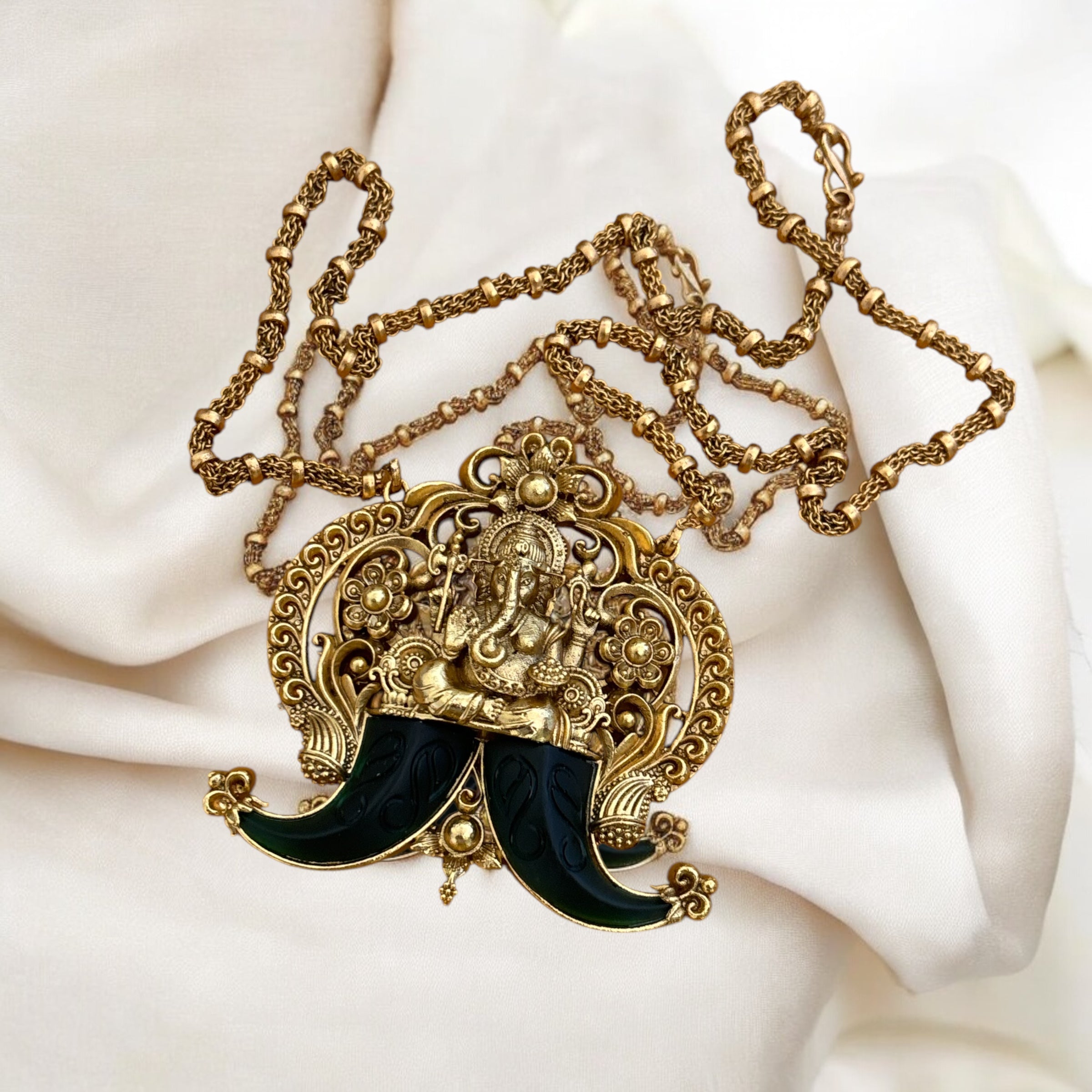 Close-up of Ganesha motif pendant on gold-tone necklace with polished surface