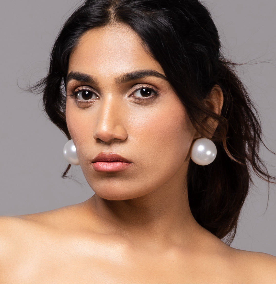 Close-up showing detailed setting of 30mm pearl earrings on gold-toned base