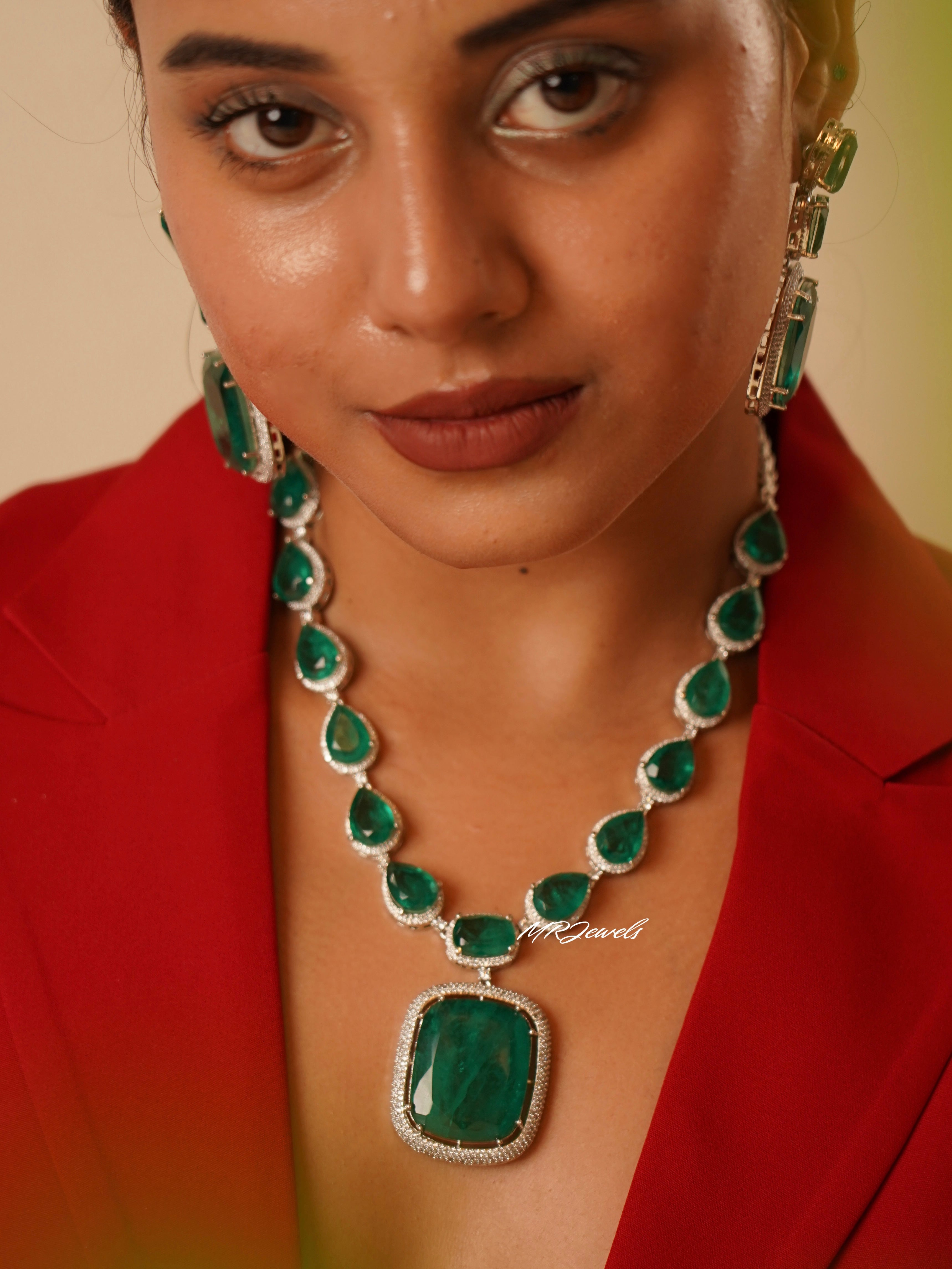 Close-up of emerald drop earrings from heirloom set with stacked green stones and crystal edge